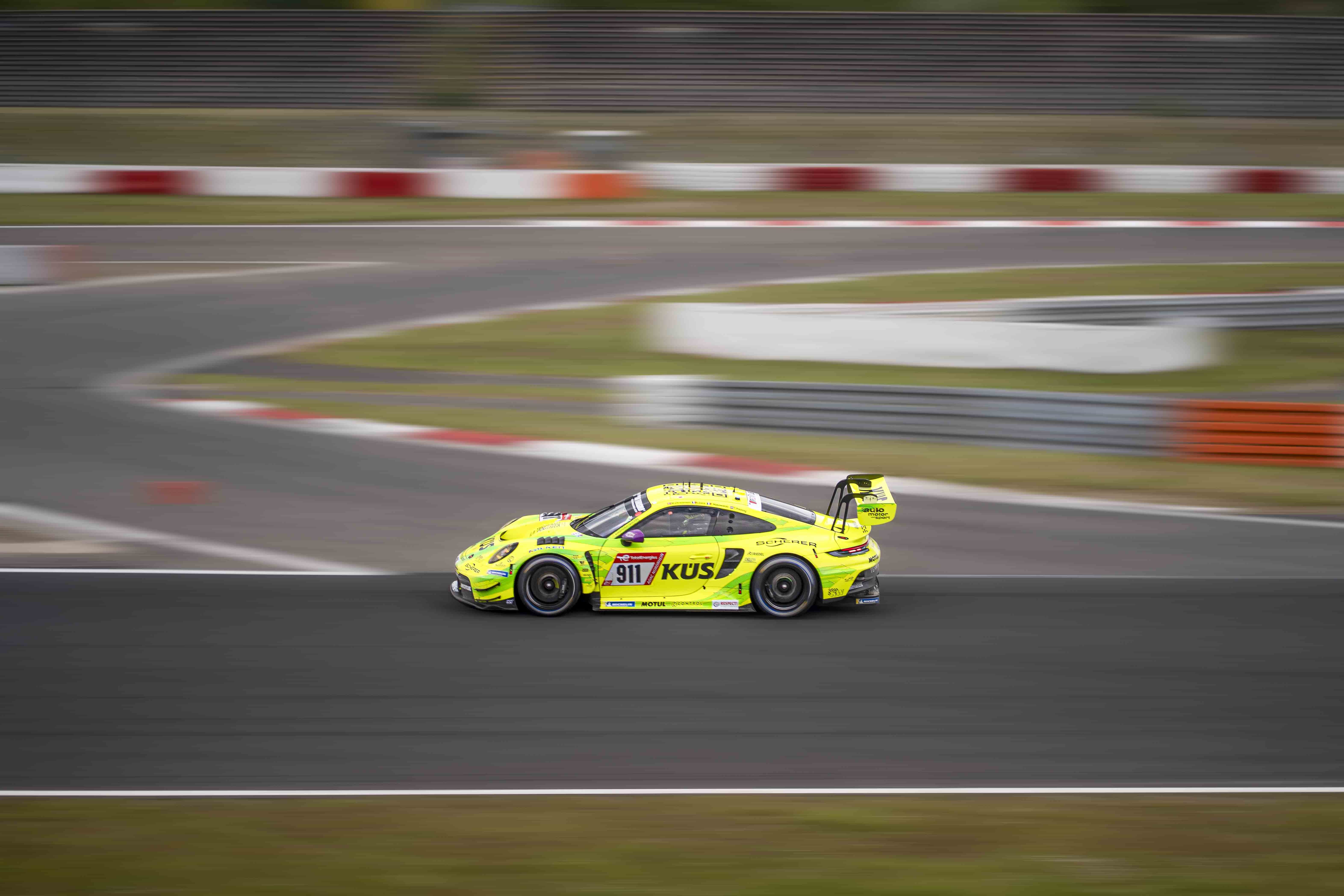 A green race car speeding round the track.