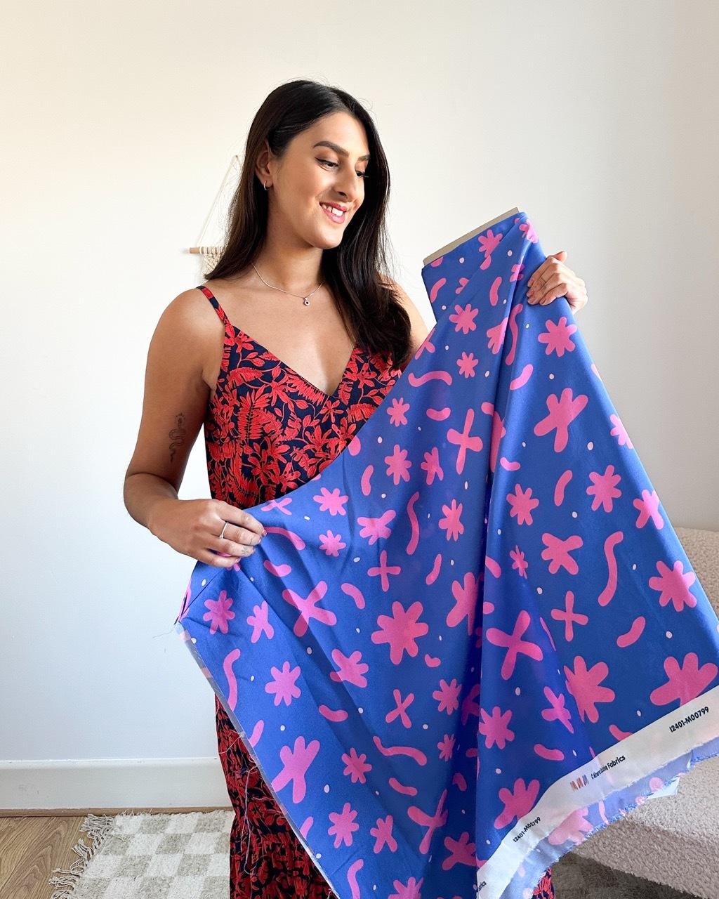 Tammy Johal stood holding a blue and pink quirky floral piece, made for the Minerva collection.