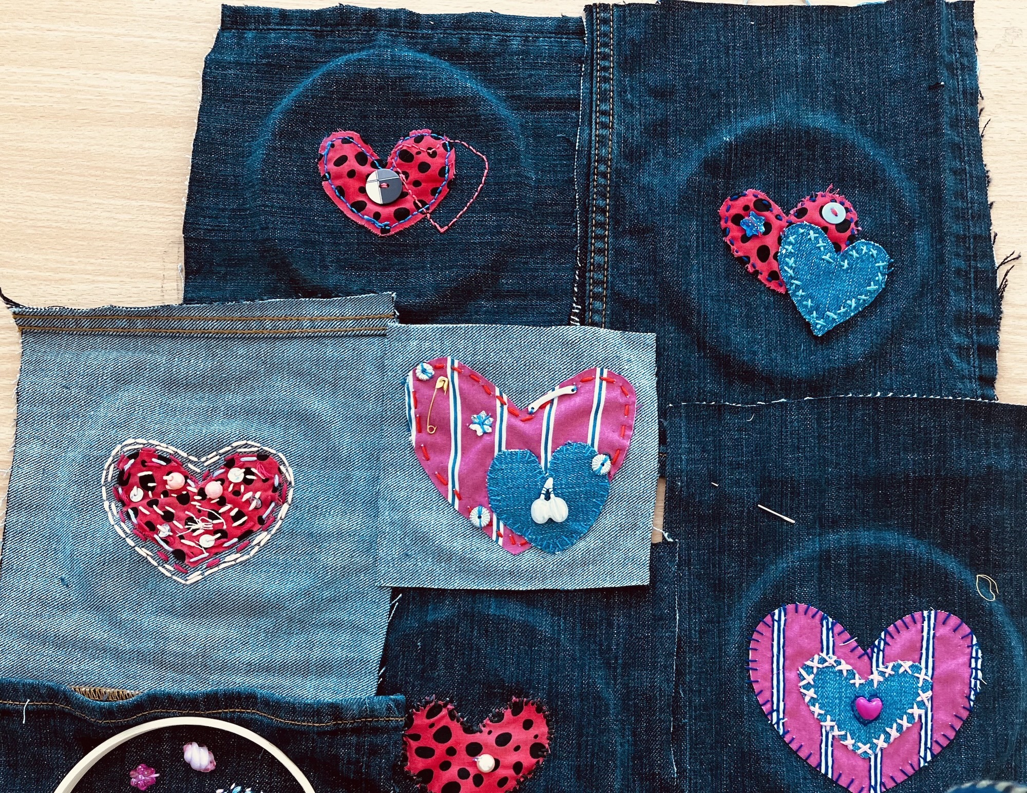 Five denim fabric patches with appliqué heart designs in red, pink, and blue patterns including polka dots and stripes
