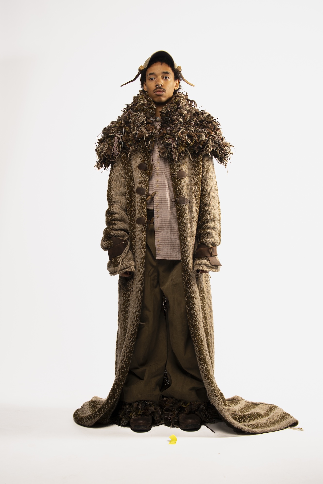 A fashion model wearing a long coat-cloak with a Medieval-style fur collar.