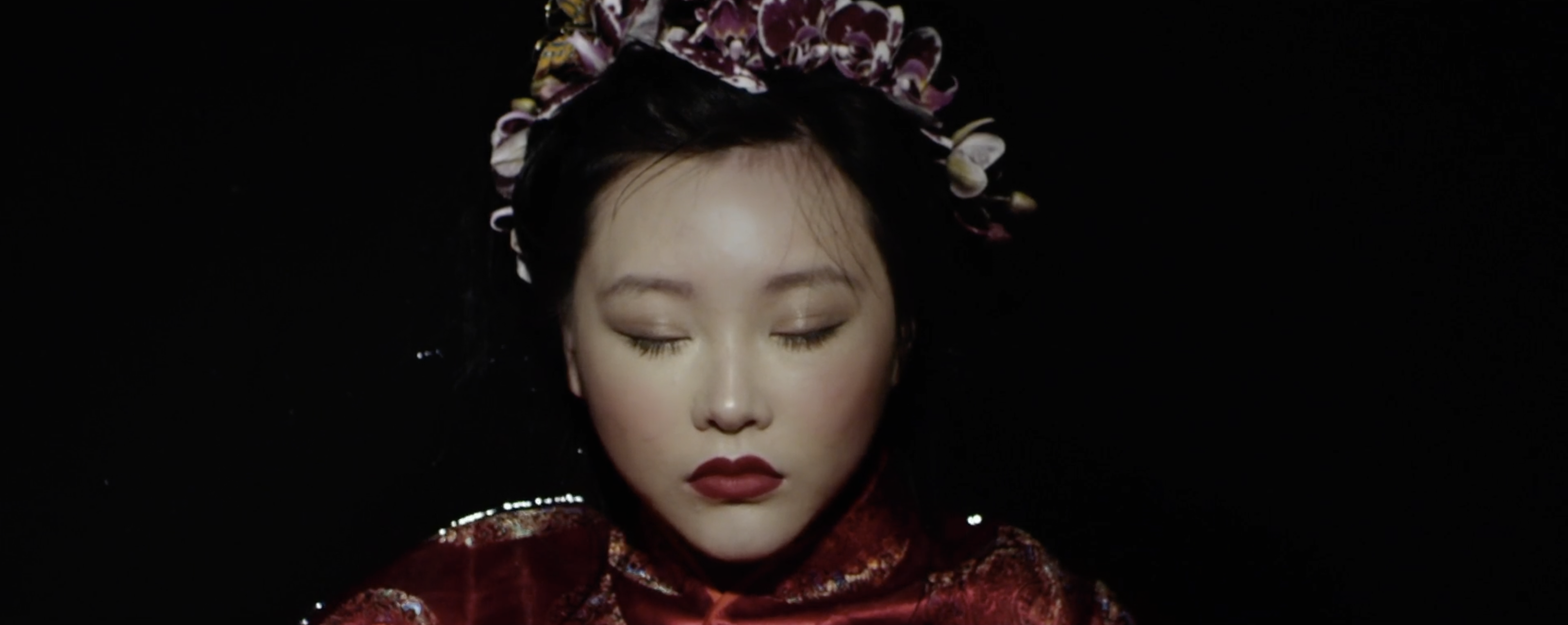 Close-up of an actress in costume with their eyes closed.