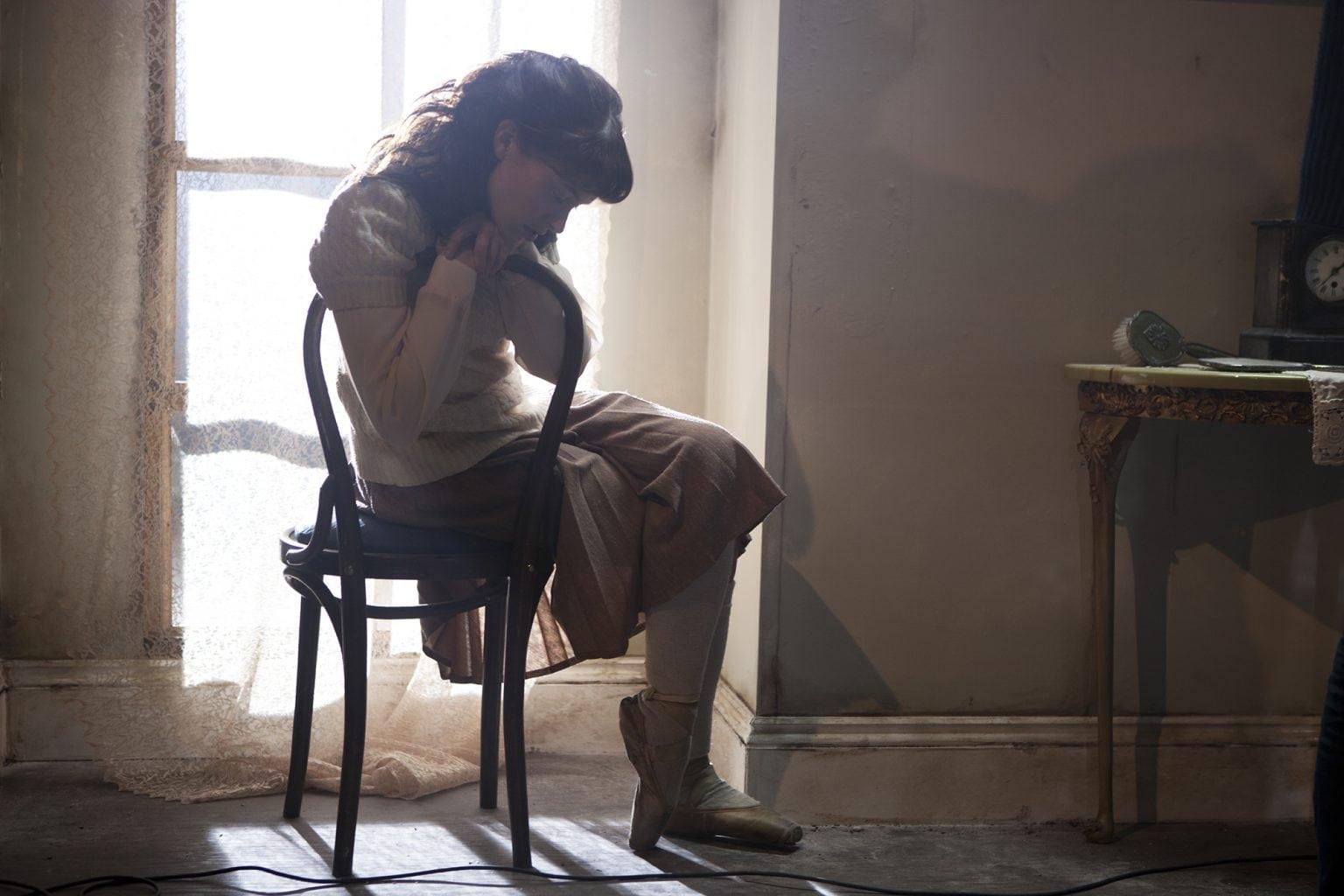 A person sits around on a chair facing away from a window.