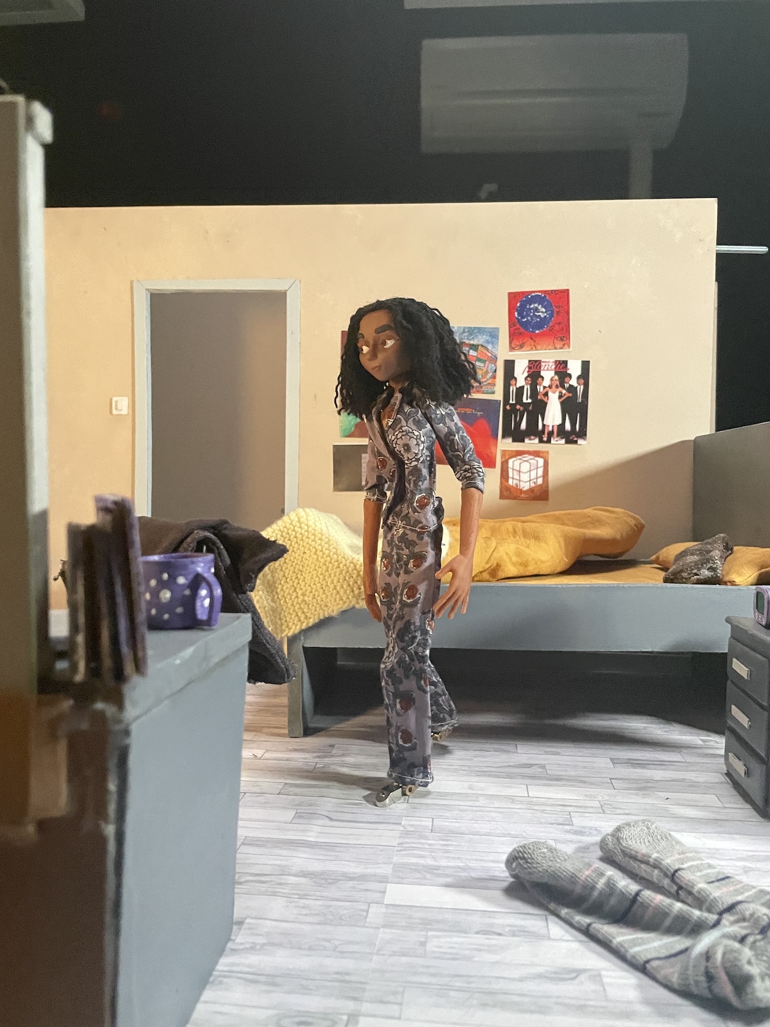 Still of a stop motion animated character getting out of bed and walking in their bedroom.