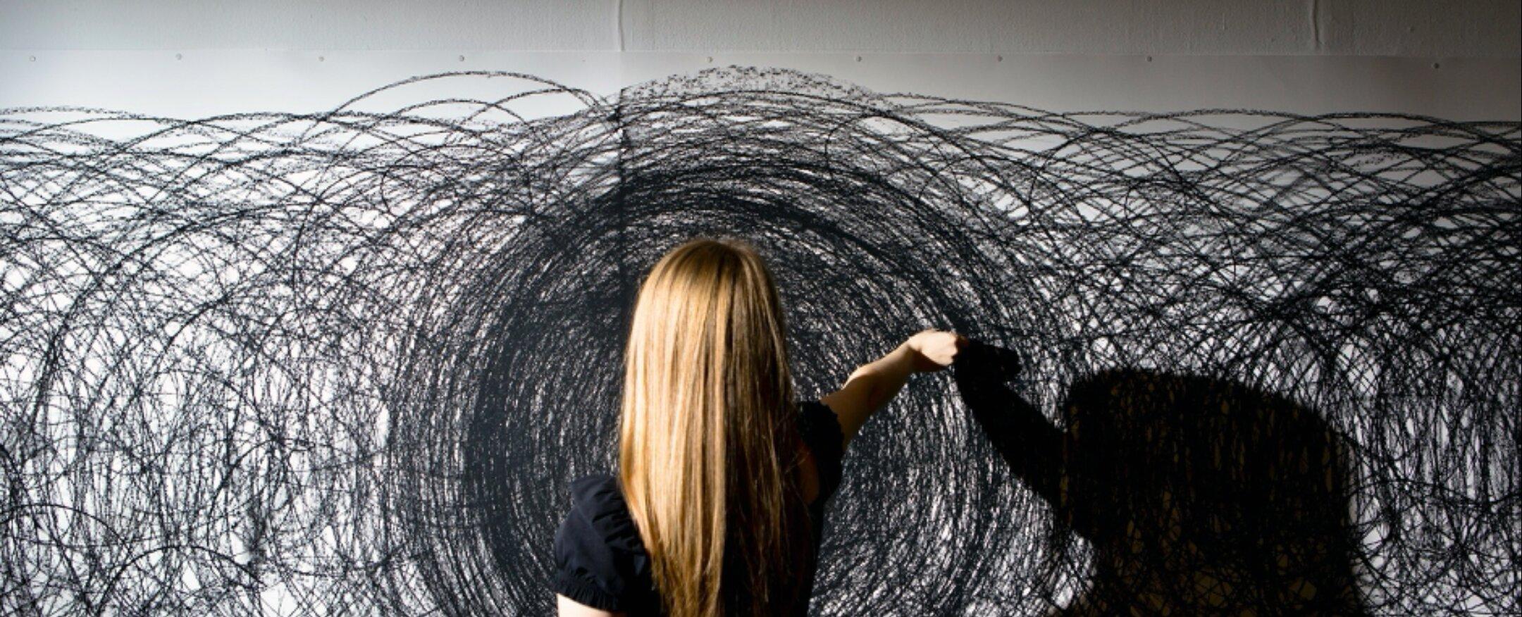 Women drawing black circles on a wall