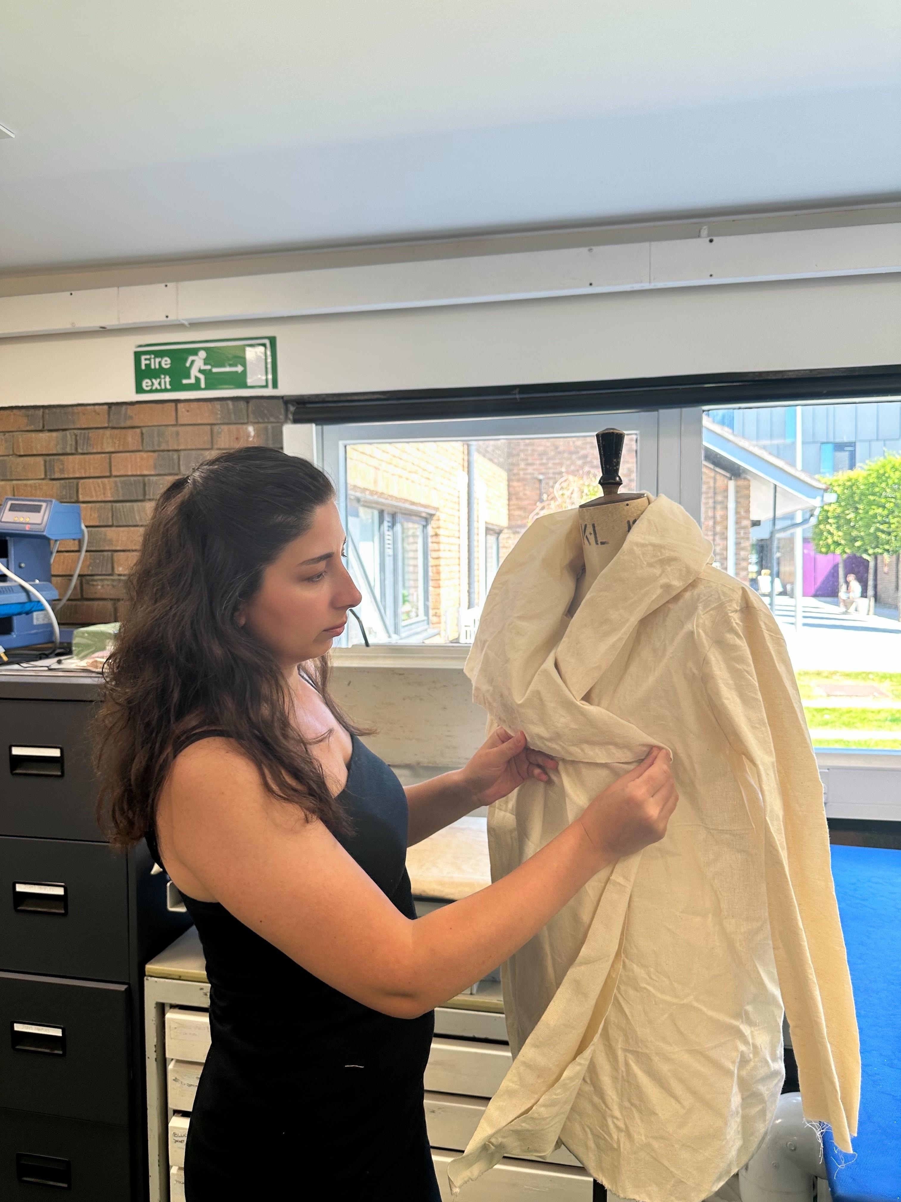 MA Digital Fashion Innovation student B Aslan fitting and adjusting a coat on a mannequin.