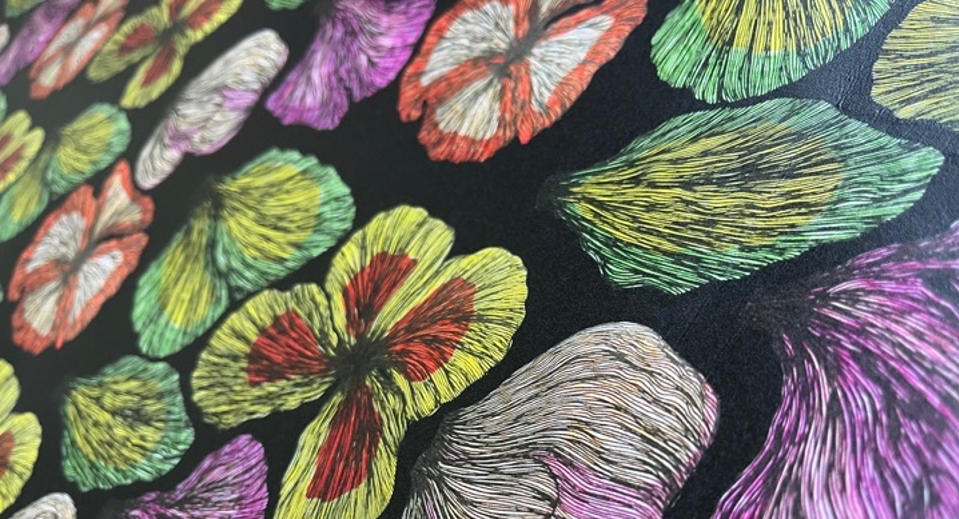 Embroidered tropical flowers in bright green, pink, purple, and coral threads on black fabric with detailed stitching patterns.
