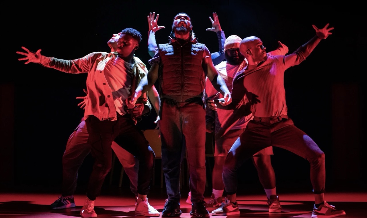 Actors on-stage reaching out from the middle under white stage lighting, red side lighting.