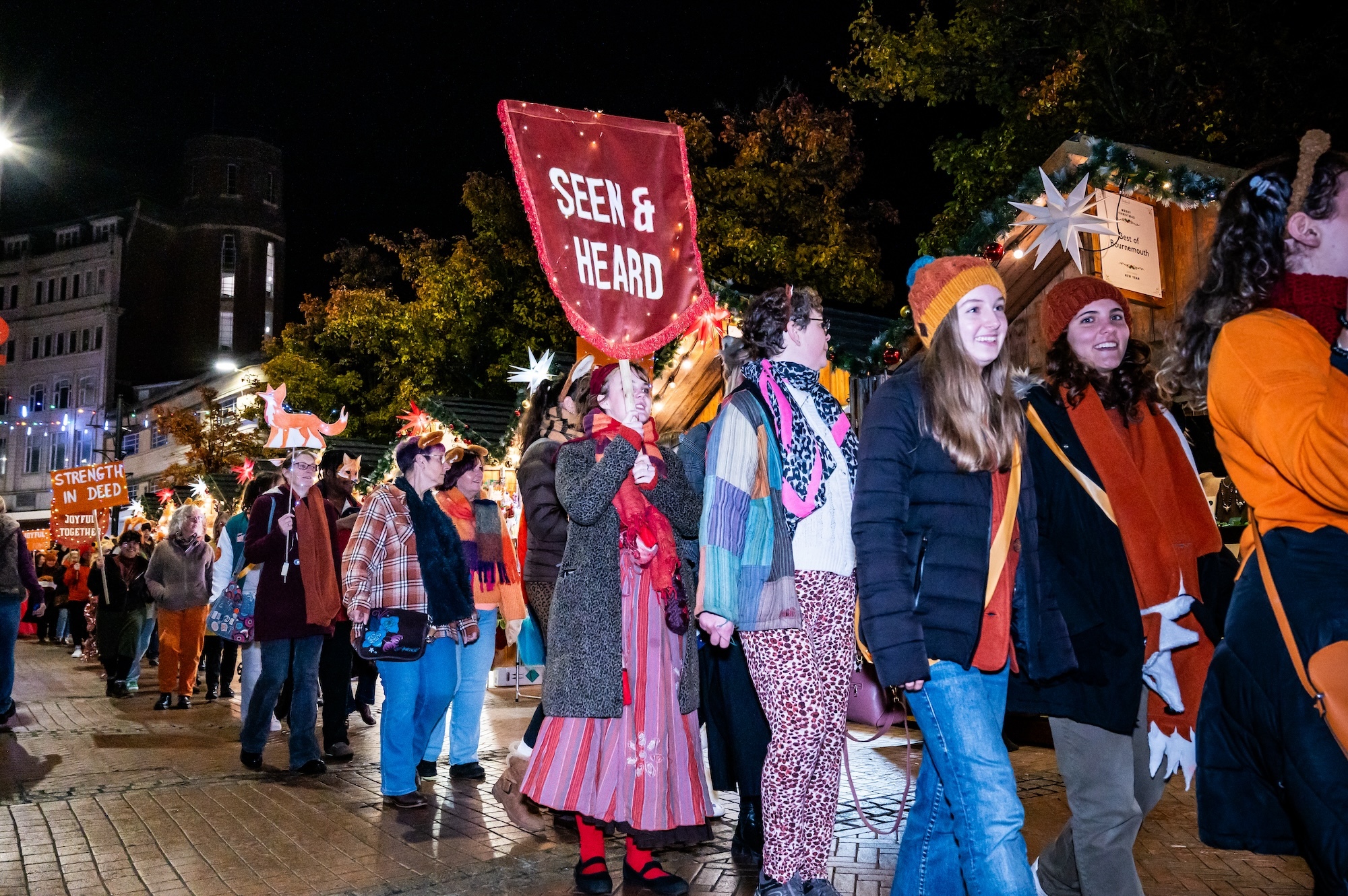 A crowd of members of the public in colourful clothing walking down Bournemouth High Street as part of FOXSTRUT 2024.