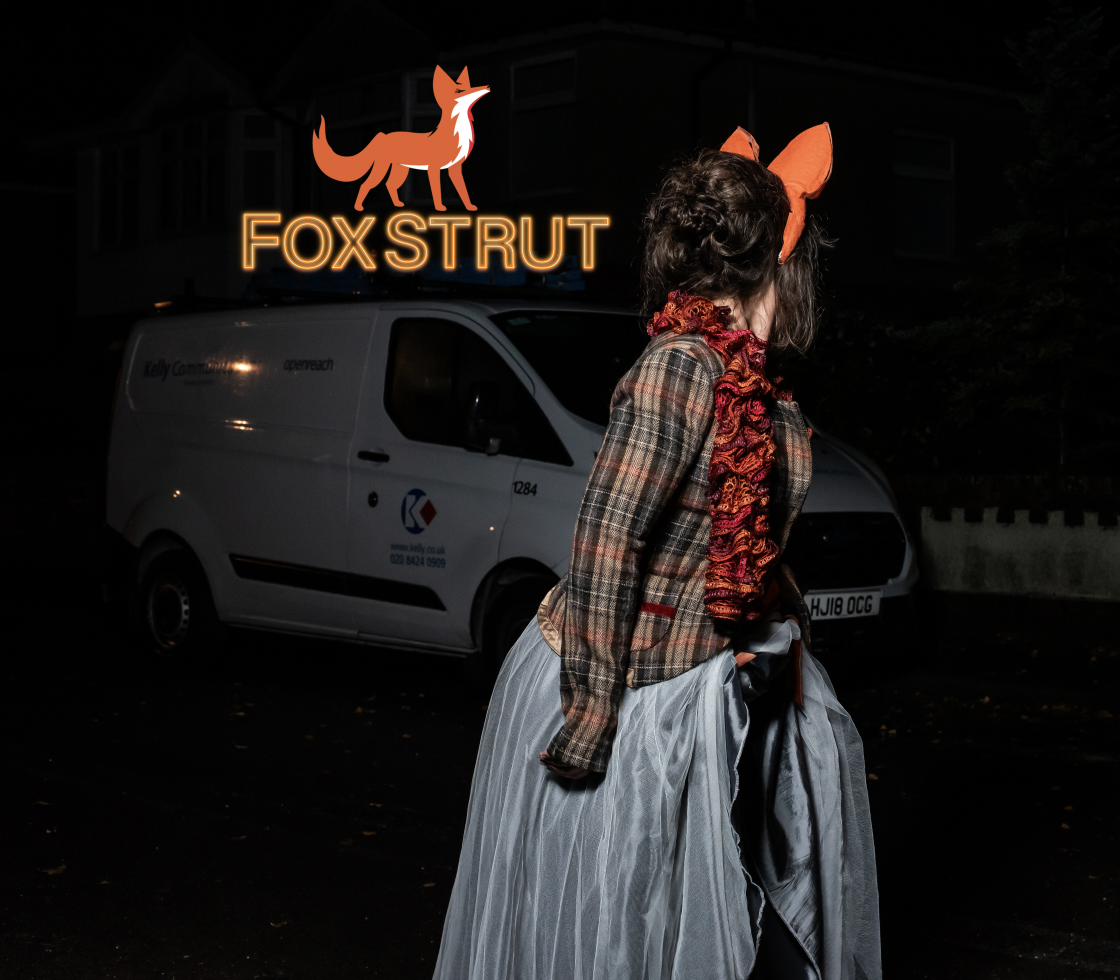 A woman in a dark street wearing fox ears and extravagant clothing, next to the 'Foxstrut' logo.