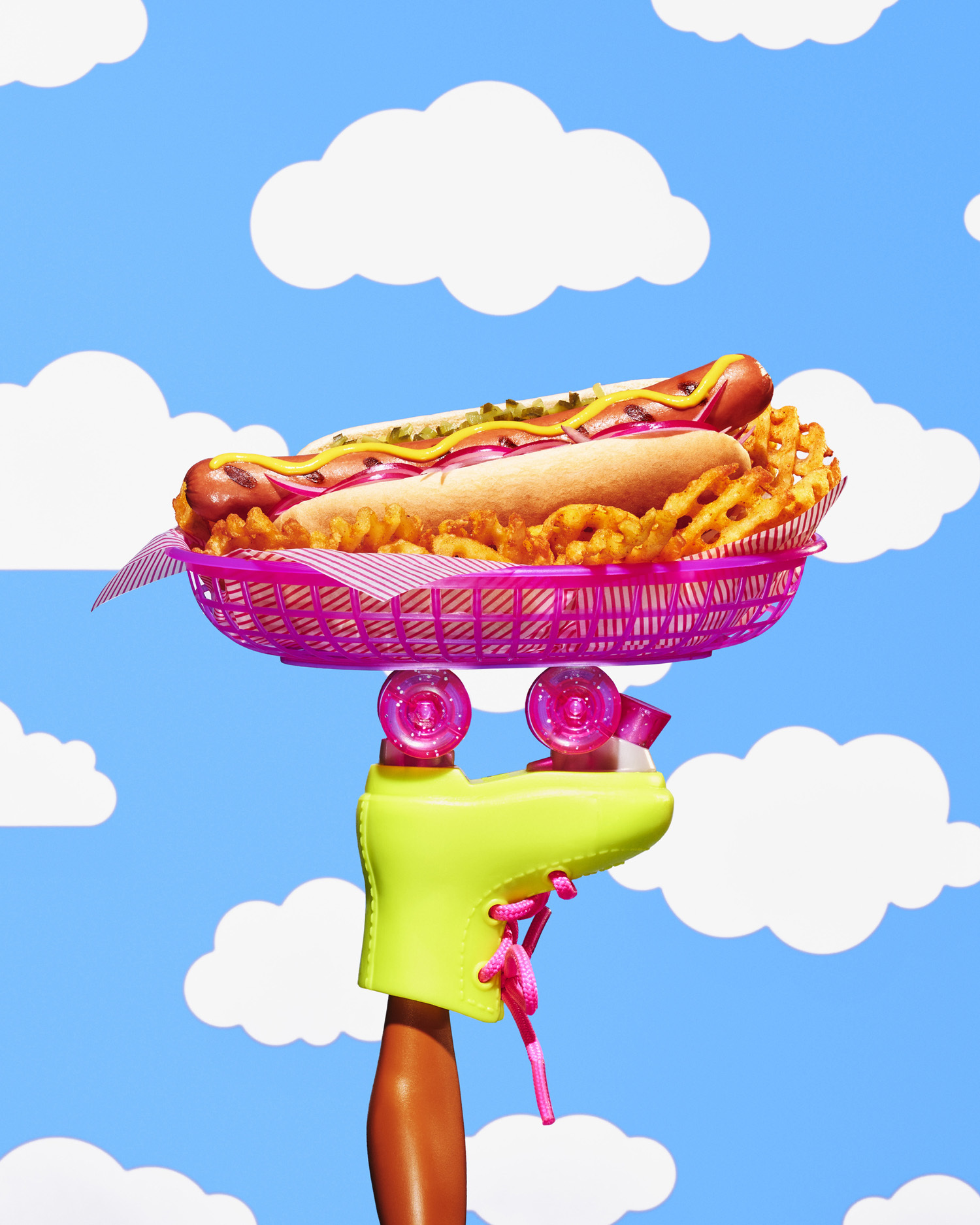 Foot of a barbie doll wearing a rollerskate, with a hot dog in a basket balanced on the wheels.