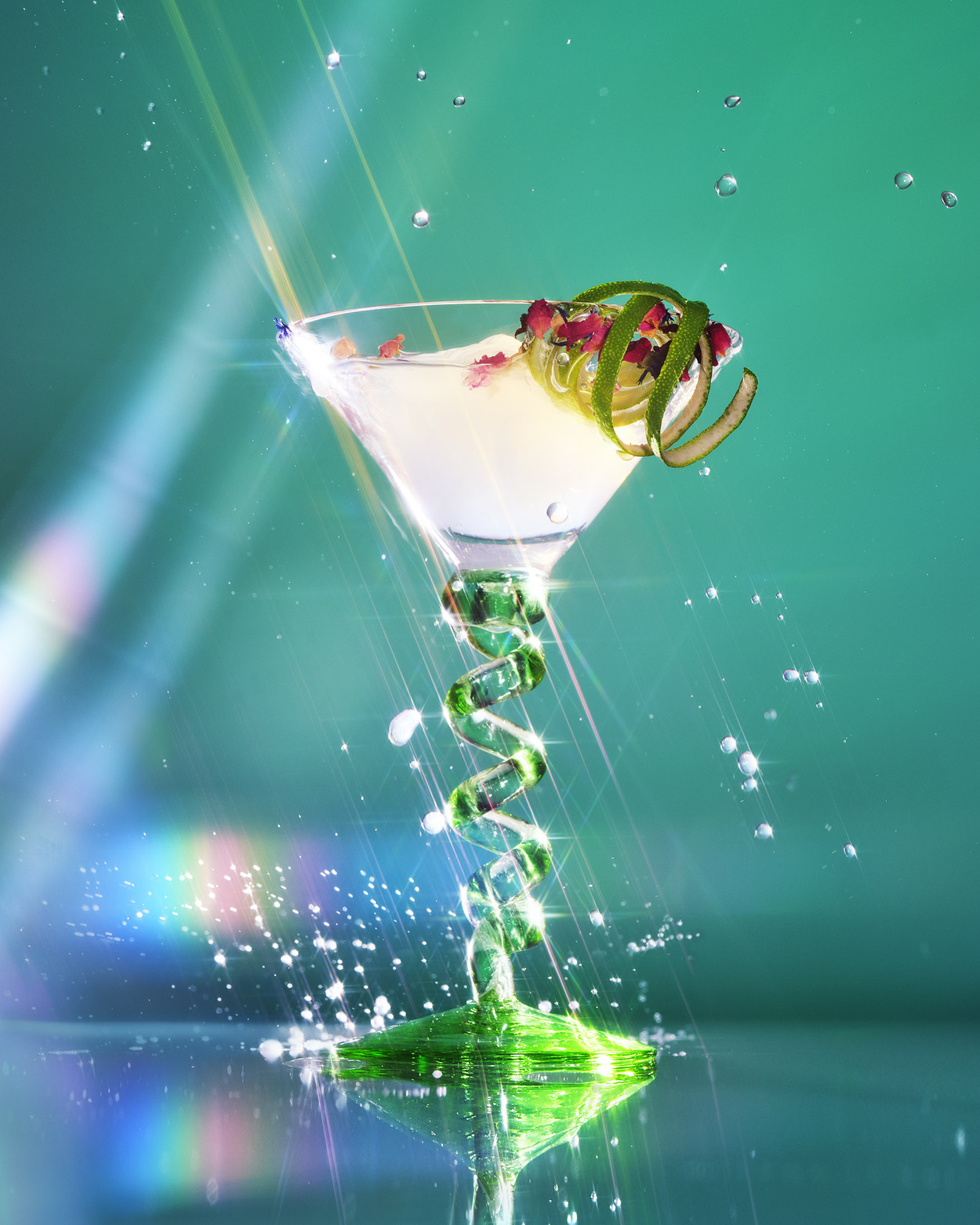 A martini in a glass with a spiral stem with water droplets spraying from it.