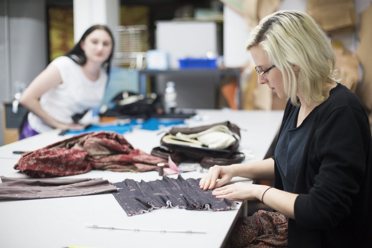 Student folding a sheet of leather on a table
