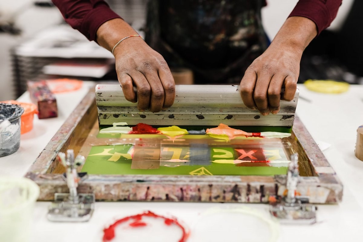 Close-up of a student's hands using screenprinting equipment.