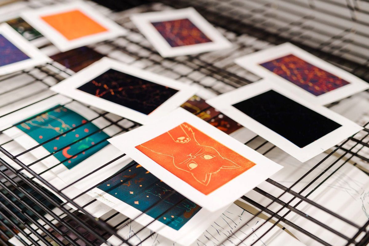 Several small screenprints drying on a rack