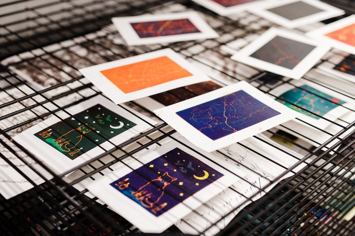 Several small screenprints drying on a rack
