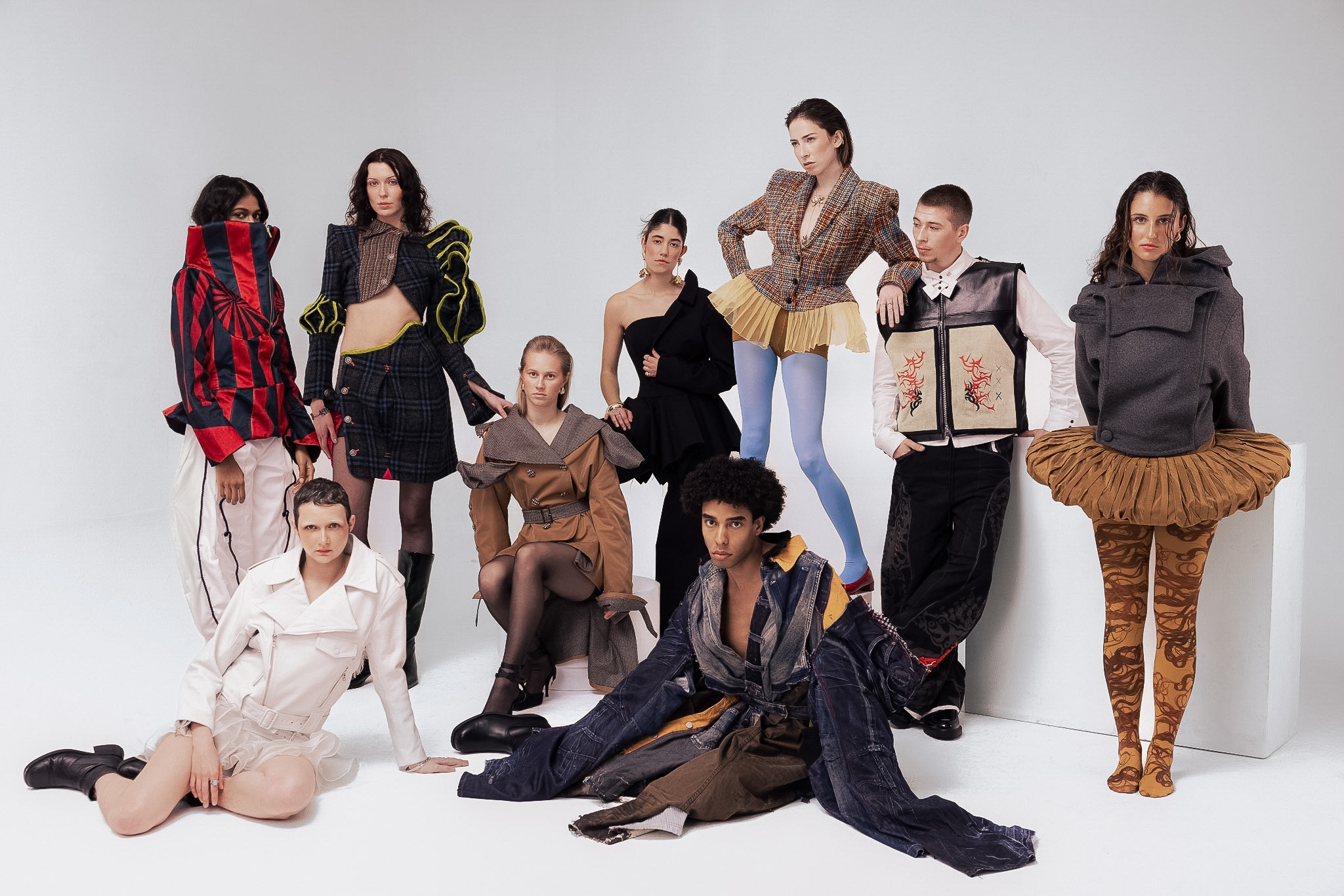 A group of nine models wearing varied, colourful outfits, pose for a fashion magazine shoot.