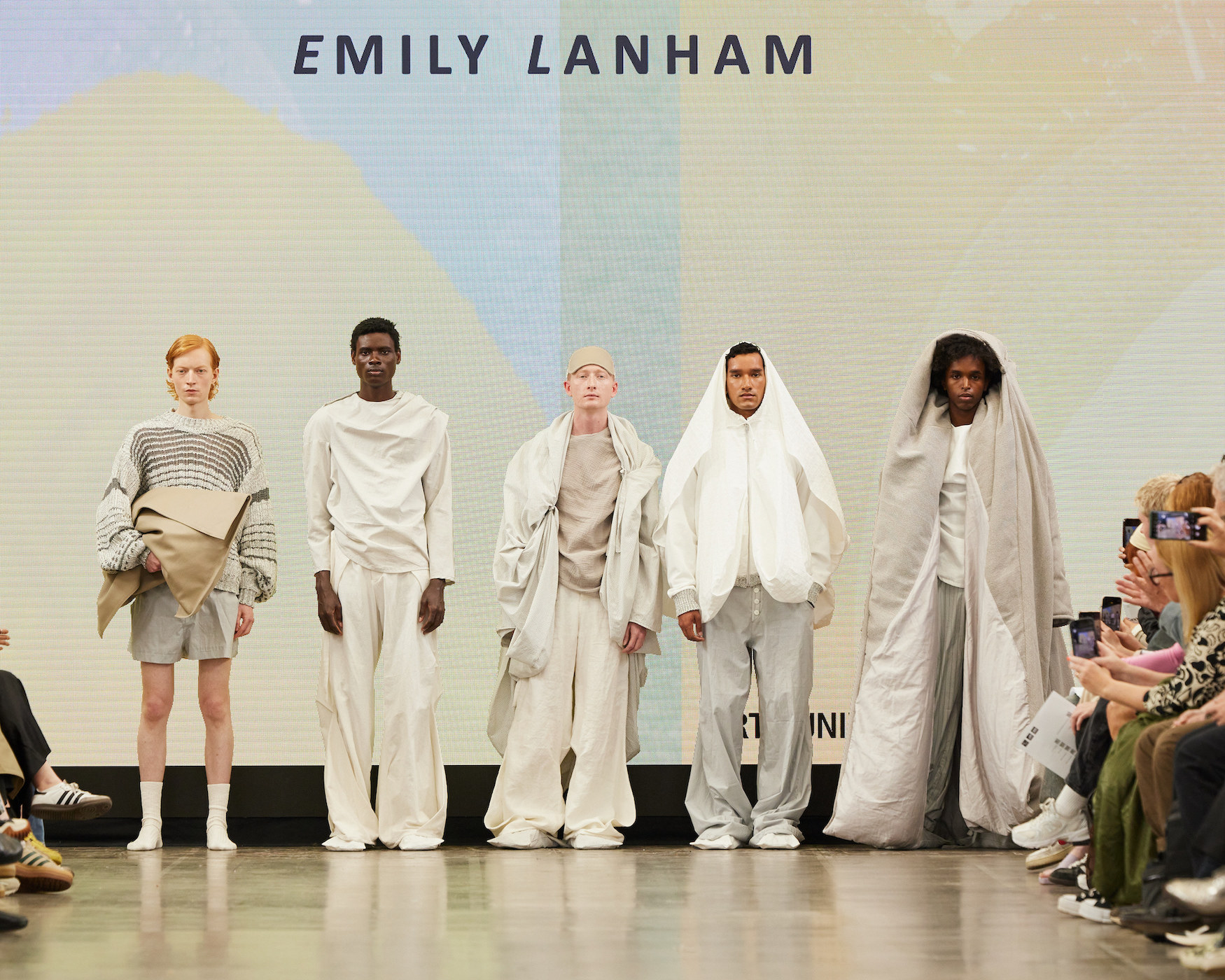 Five models lined up on the catwalk at Graduate Fashion Week 2024, wearing creations by BA (Hons) Fashion student E. Lanham, inspired by bedding.