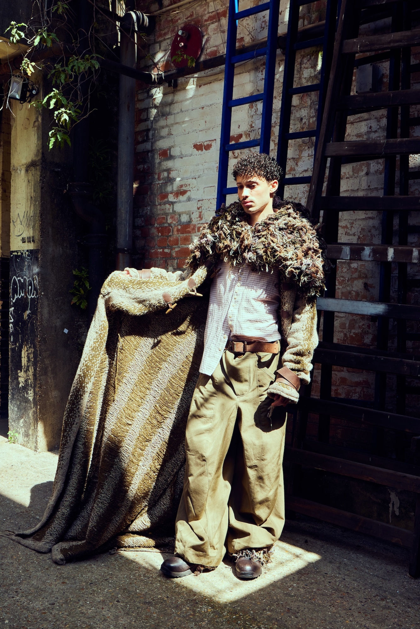A model wearing a Mediaeval-style fur-collared cloak posing for a photo in a fashion shoot.