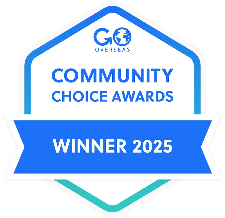 Hexagonal badge with white background, blue border and ribbon. Text reads "GO OVERSEAS COMMUNITY CHOICE AWARDS WINNER 2025" in blue.