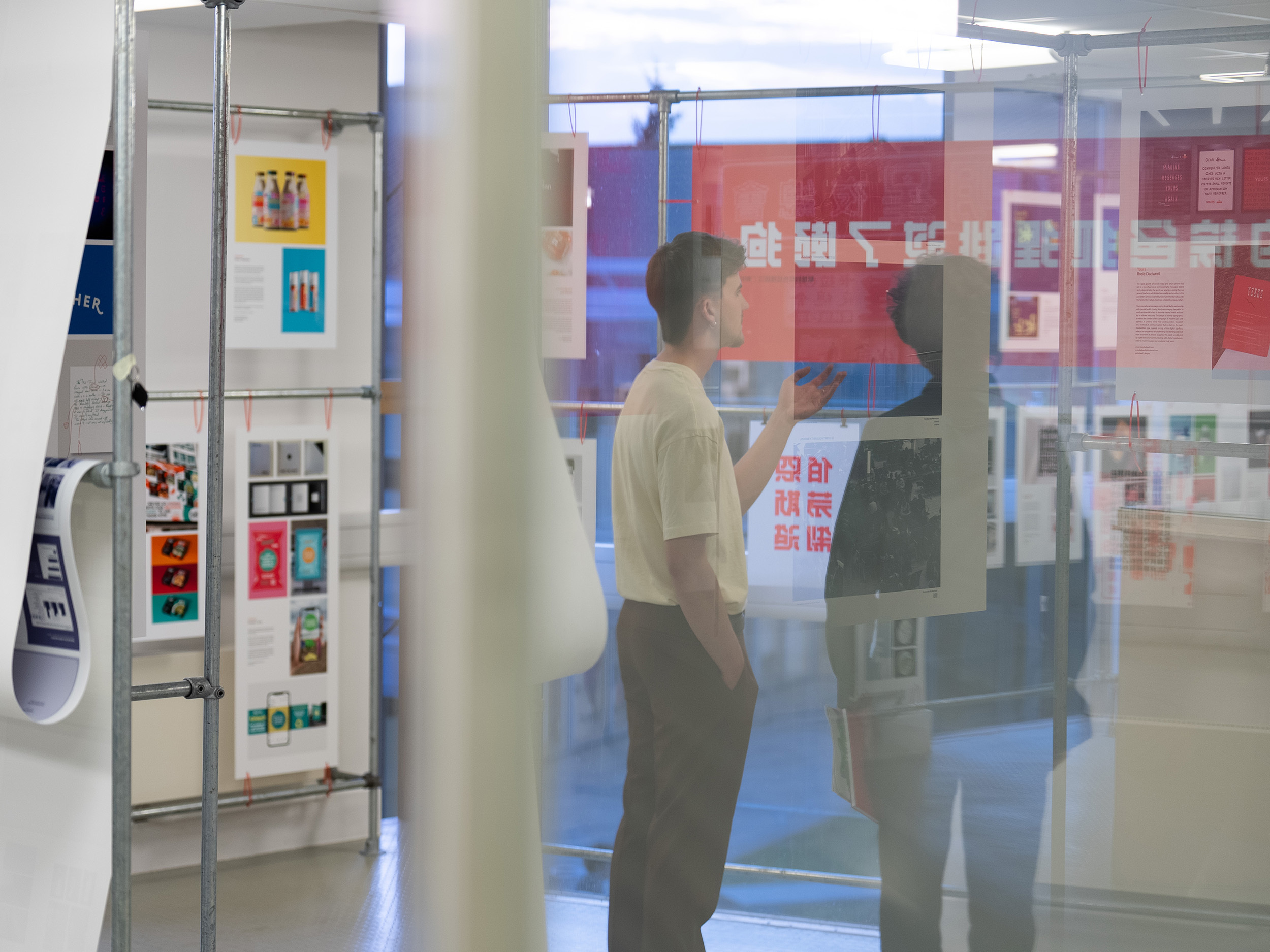 Two people standing and discussing work in a gallery space.