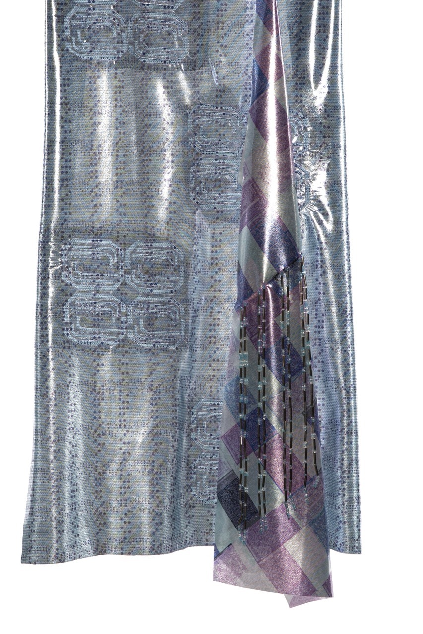 Silver sequined fabric with iridescent surface reflecting light, draped and folded against white background.