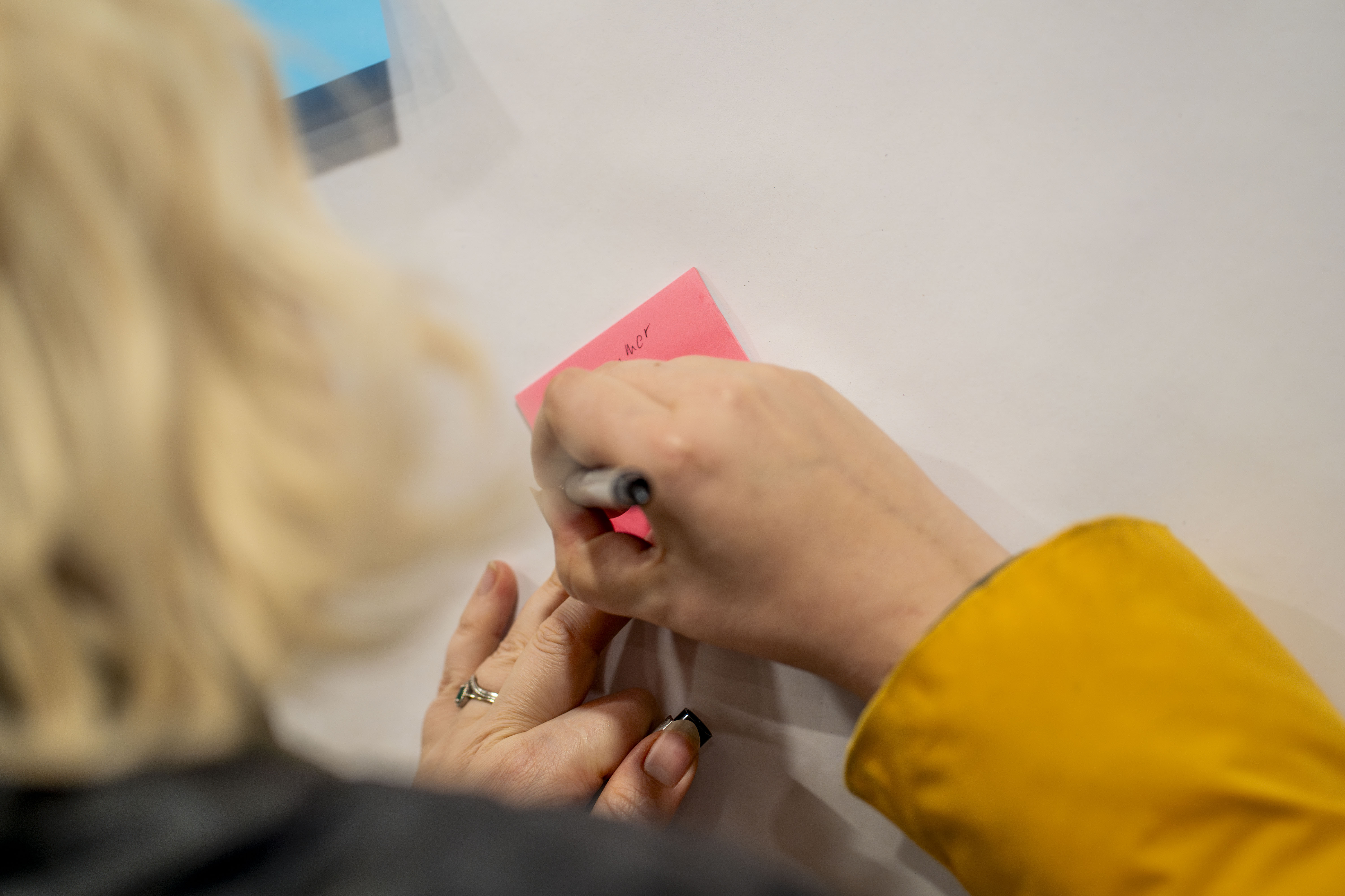 Hand writing feedback on a post-it note