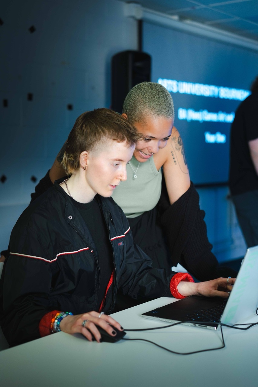 Students interacting with a laptop, one using a wired mouse.