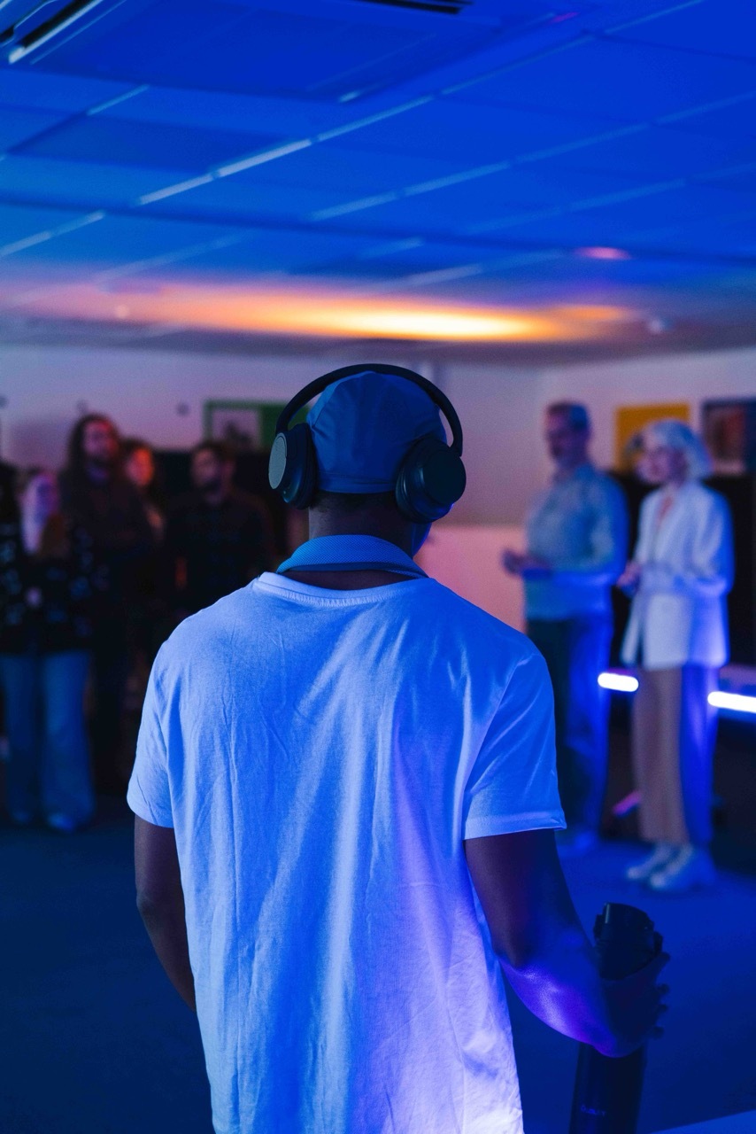 Student wearing a white t-shirt and headphones, dim blue and orange light.
