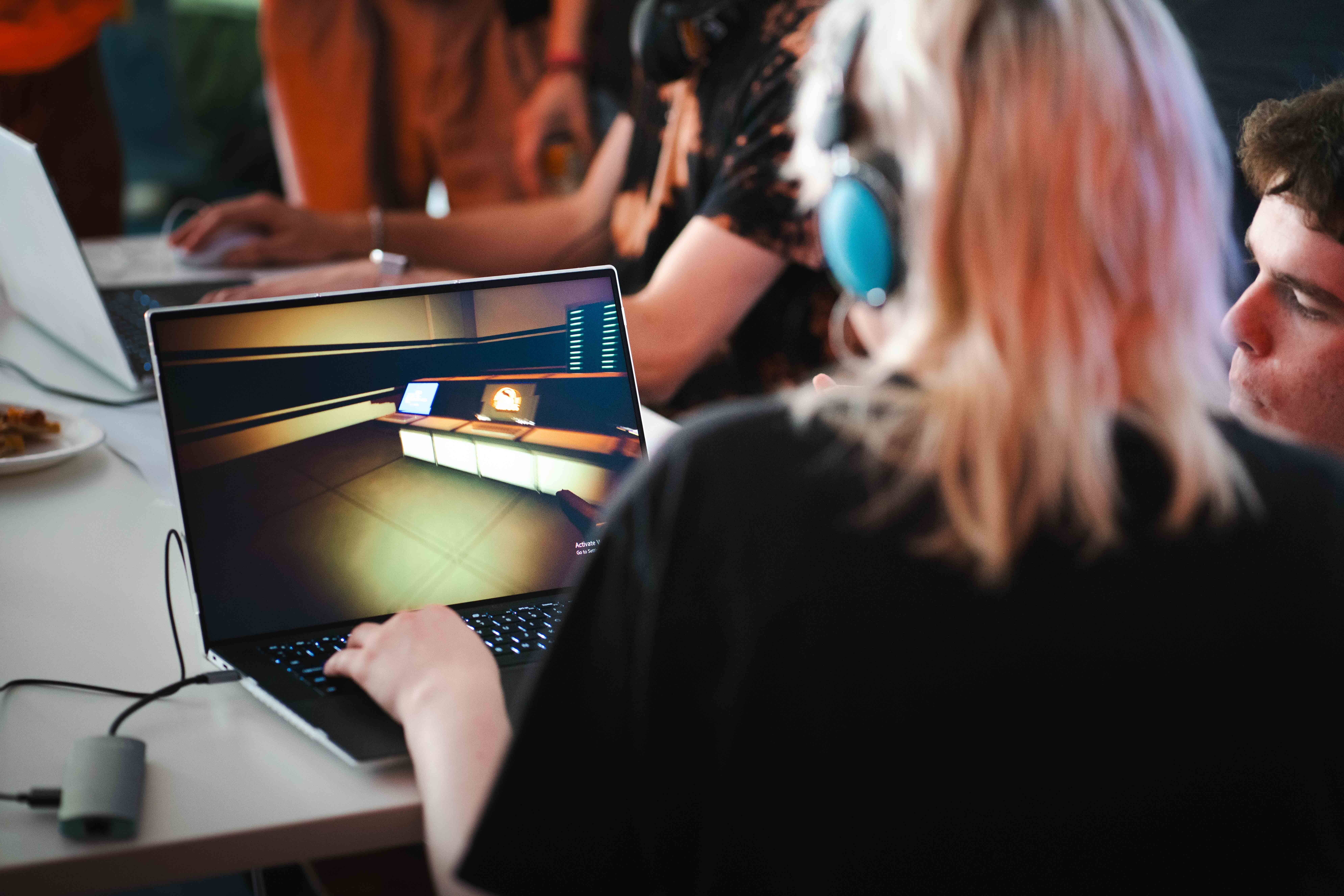 Close-up of two students playing a first-person shooter game on a laptop, at a BA (Hons) Games Art and Design exhibition at Arts University Bournemouth.