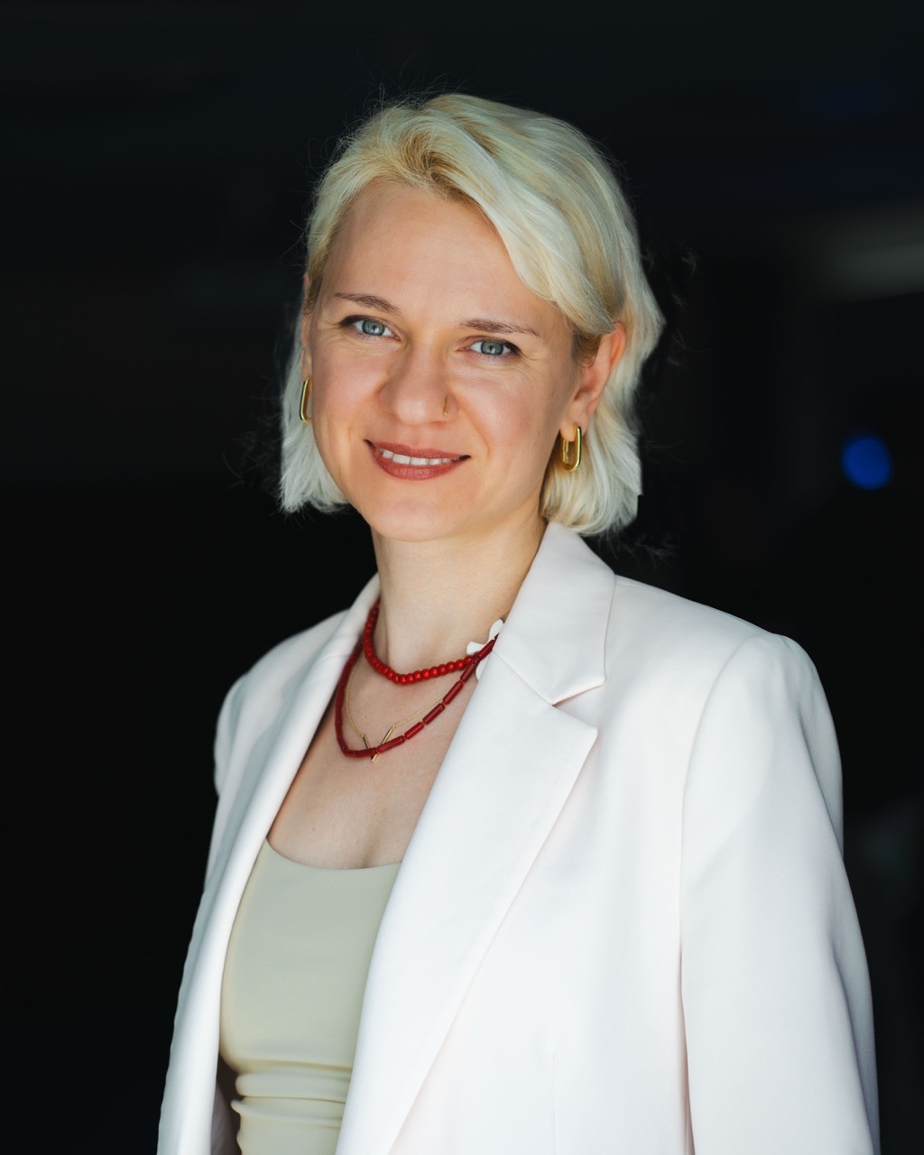 Dr Alina Potemska wearing a white blazer, dark background