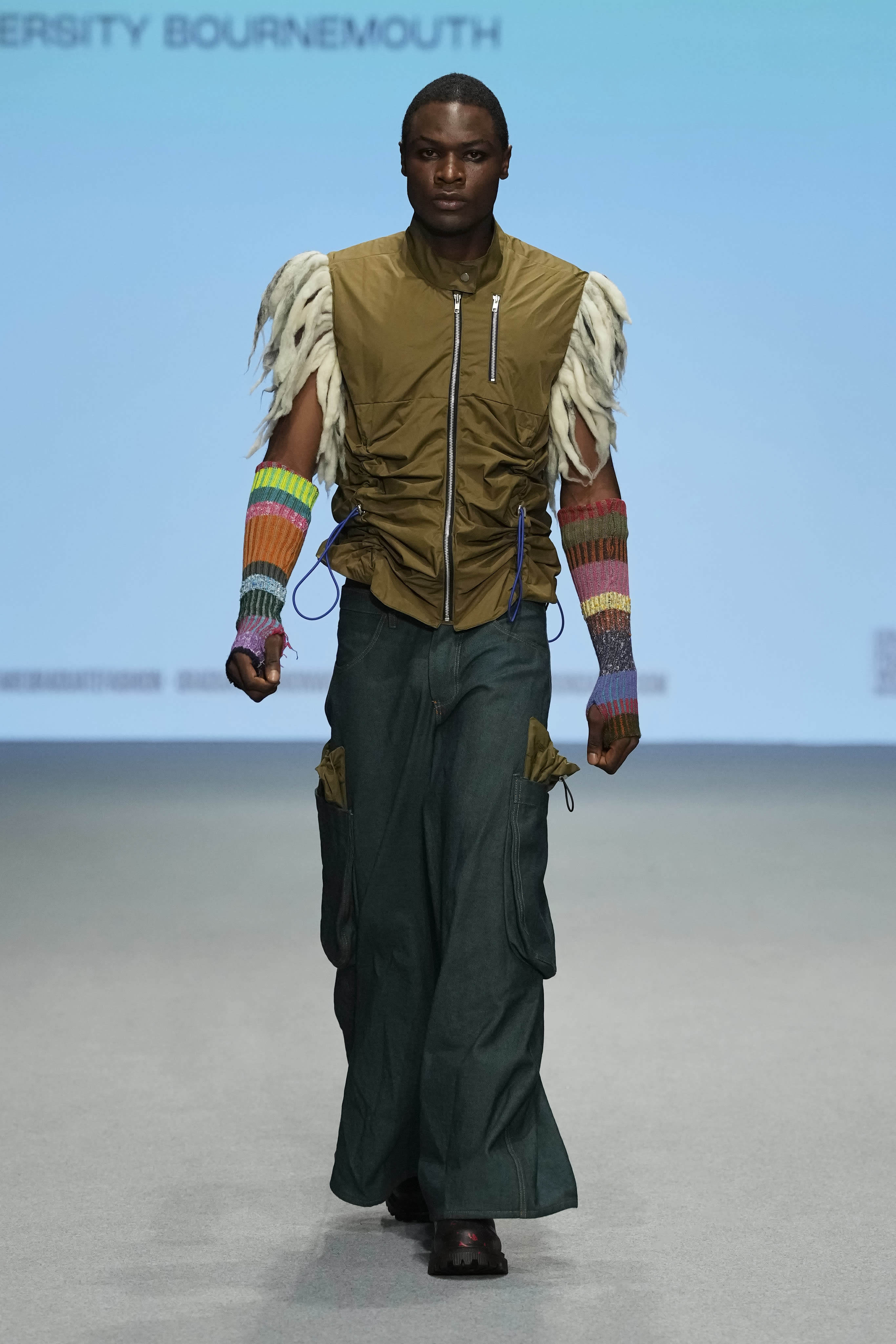 Male model walking down a runway at Graduate Fashion Week International 2023 in Dubai. They are wearing garments featured in the 51//NORTH collection by Lucy James.