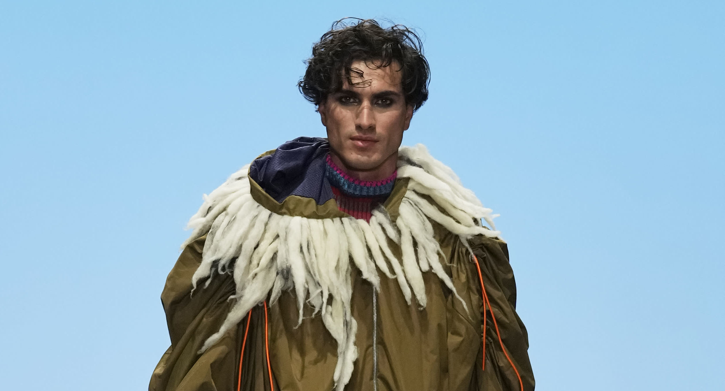 Male model walking down a runway at Graduate Fashion Week International 2023 in Dubai. They are wearing garments featured in the 51//NORTH collection by Lucy James.