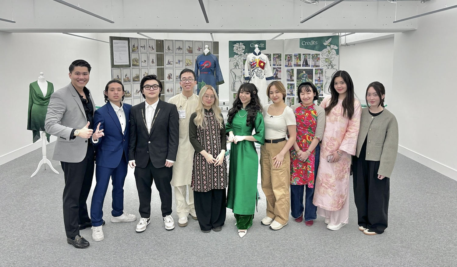 A large team of people including an AUB MA Illustration student poses for a photo in an exhibition space for the Green Fashion pop-up exhibition.