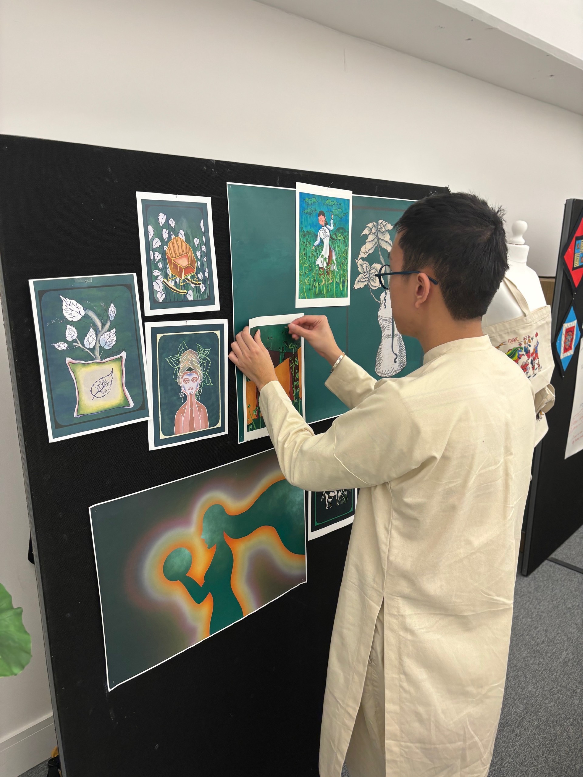 M H Nguyen sticking an illustration in place on a gallery wall at the Green Fashion pop-up exhibition.