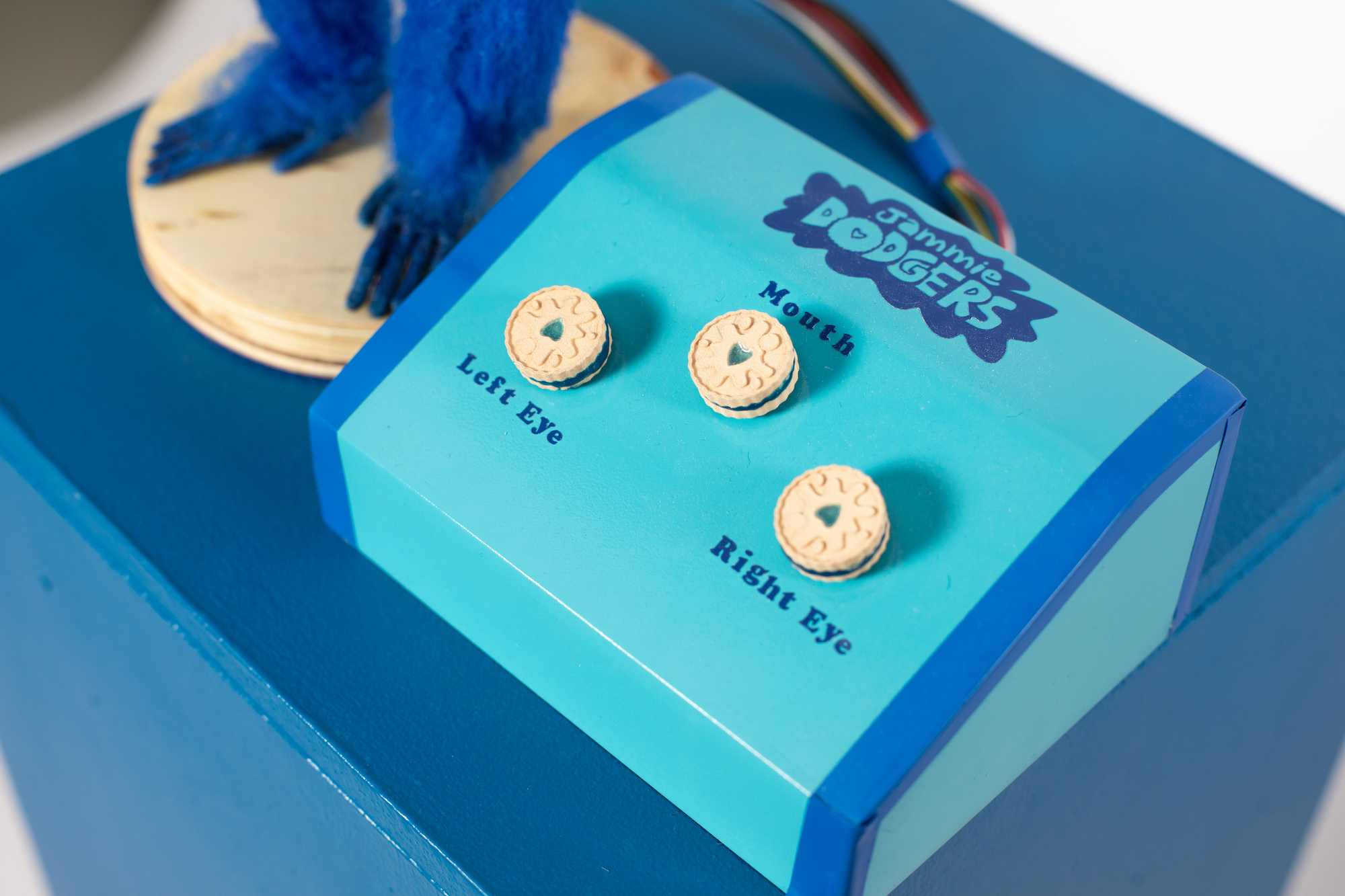 Blue control box for an animatronic puppet. Three knobs on the box are shaped like Jammie Dodger biscuits.