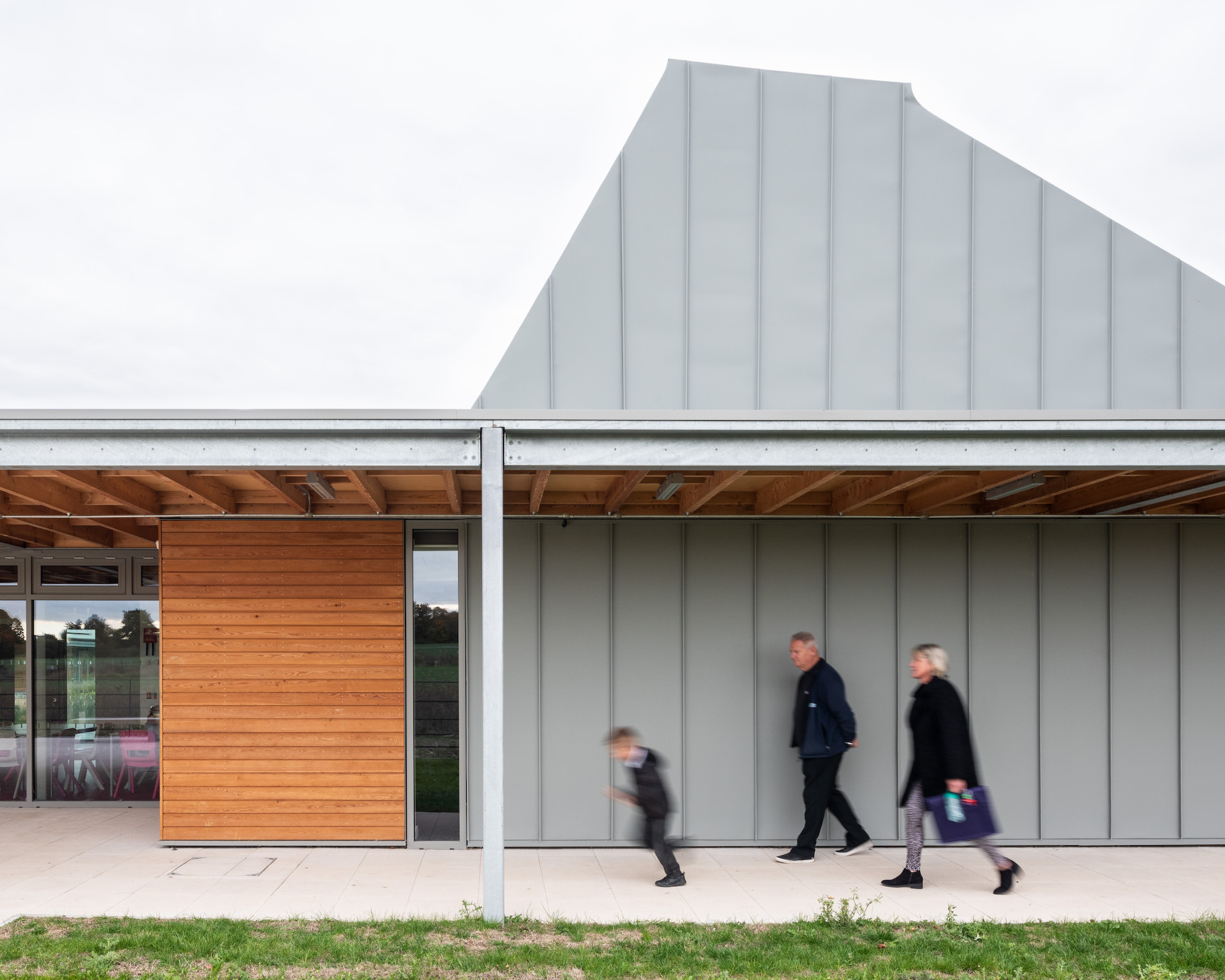 A man, woman and child walking outside an abstract-looking building.