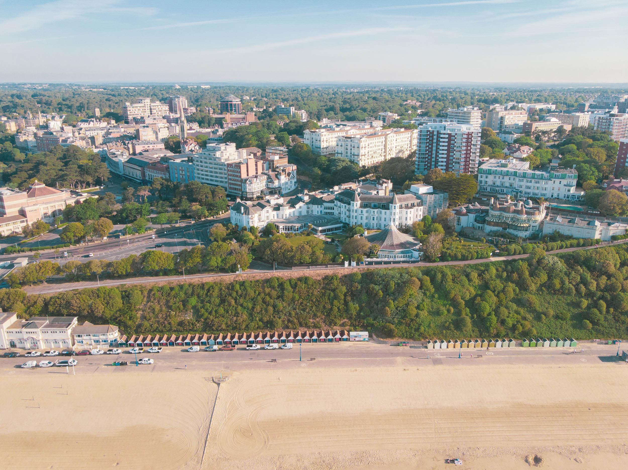 Aerial photo of a sandy beach, promenade and town buildings in the distance.