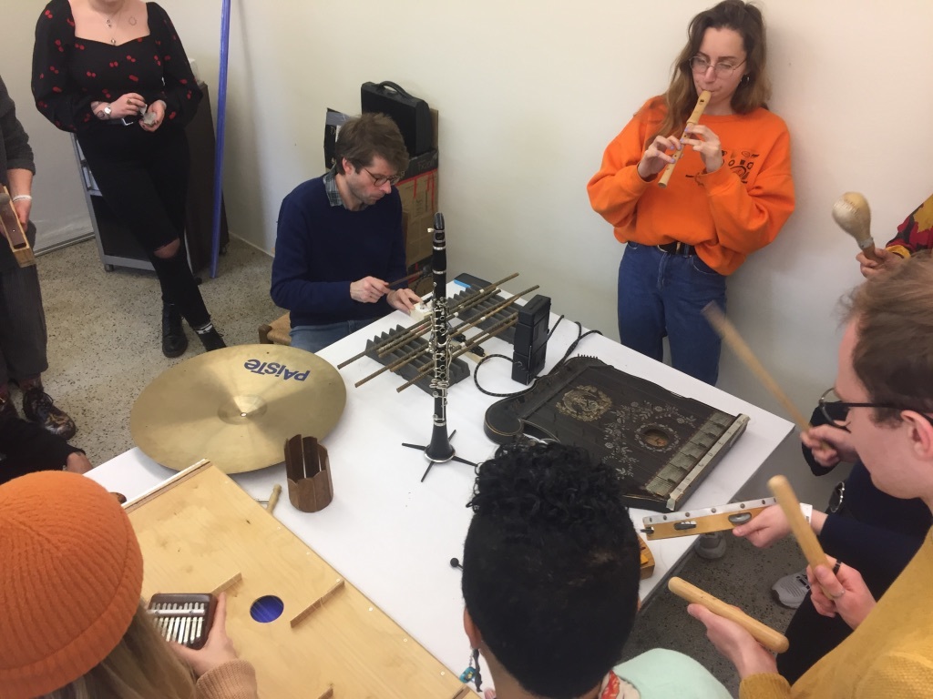 A group of people sat around a table playing musical instruments.