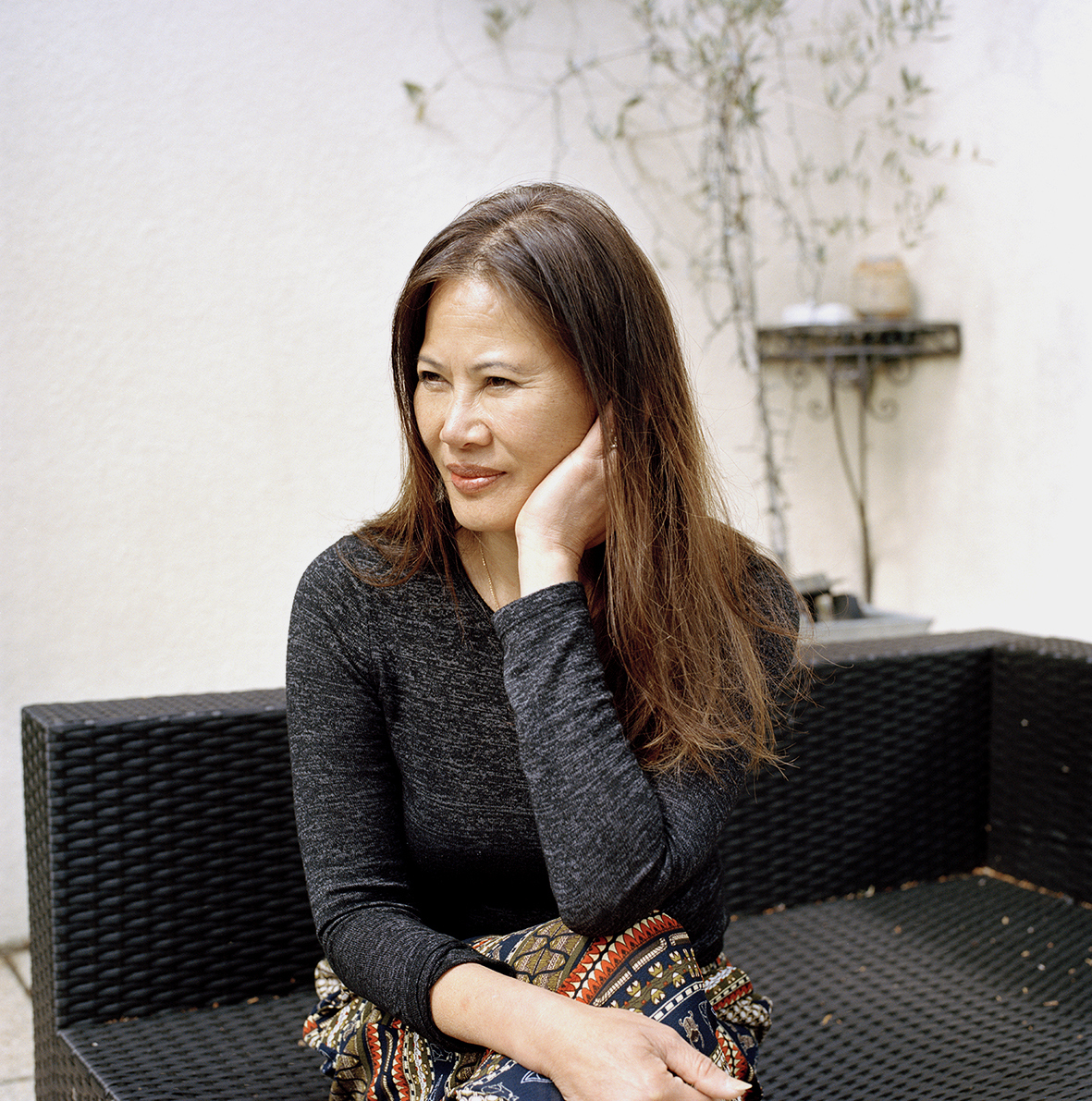Portrait of a person sitting on an outdoor wicker bench.