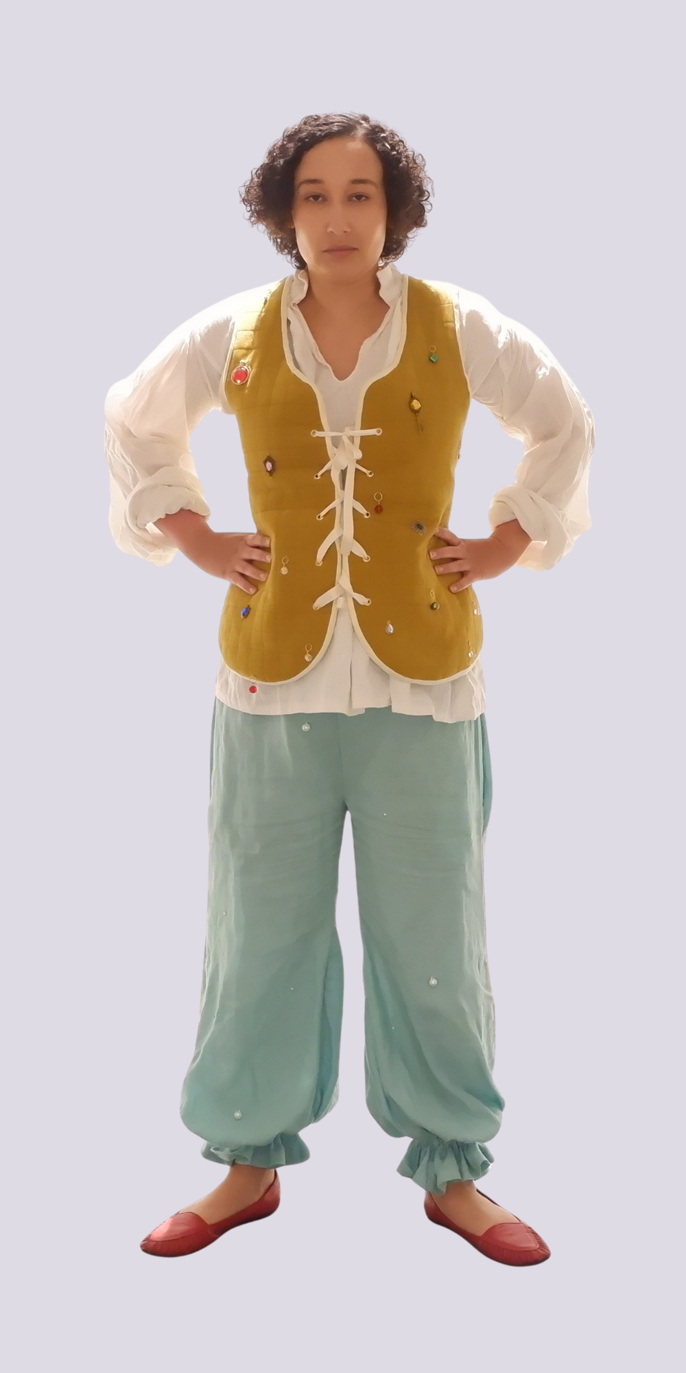 Person in period costume with golden waistcoat, white lace-up shirt, seafoam green trousers, and brown shoes against pale background.