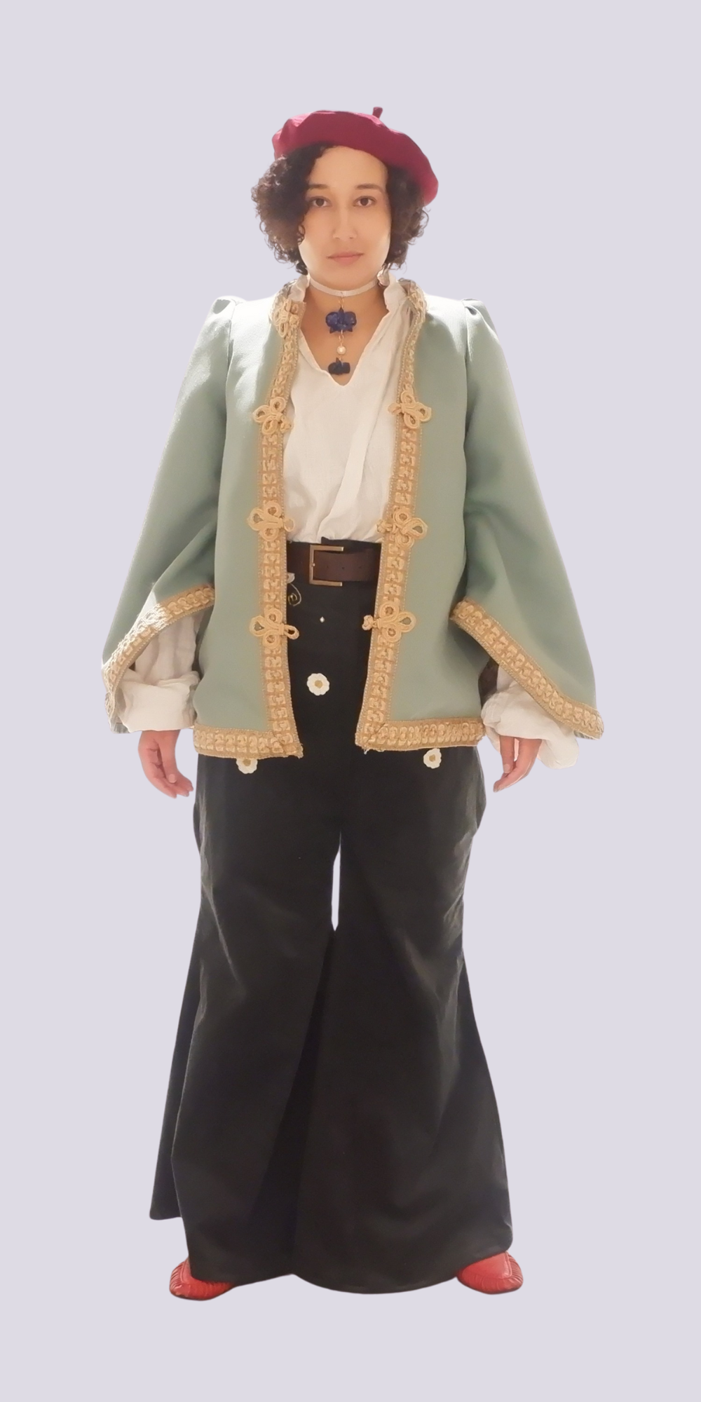 Person in Elizabethan costume: red velvet beret, sage green doublet with gold trim, white ruffled shirt, dark breeches, red shoes.