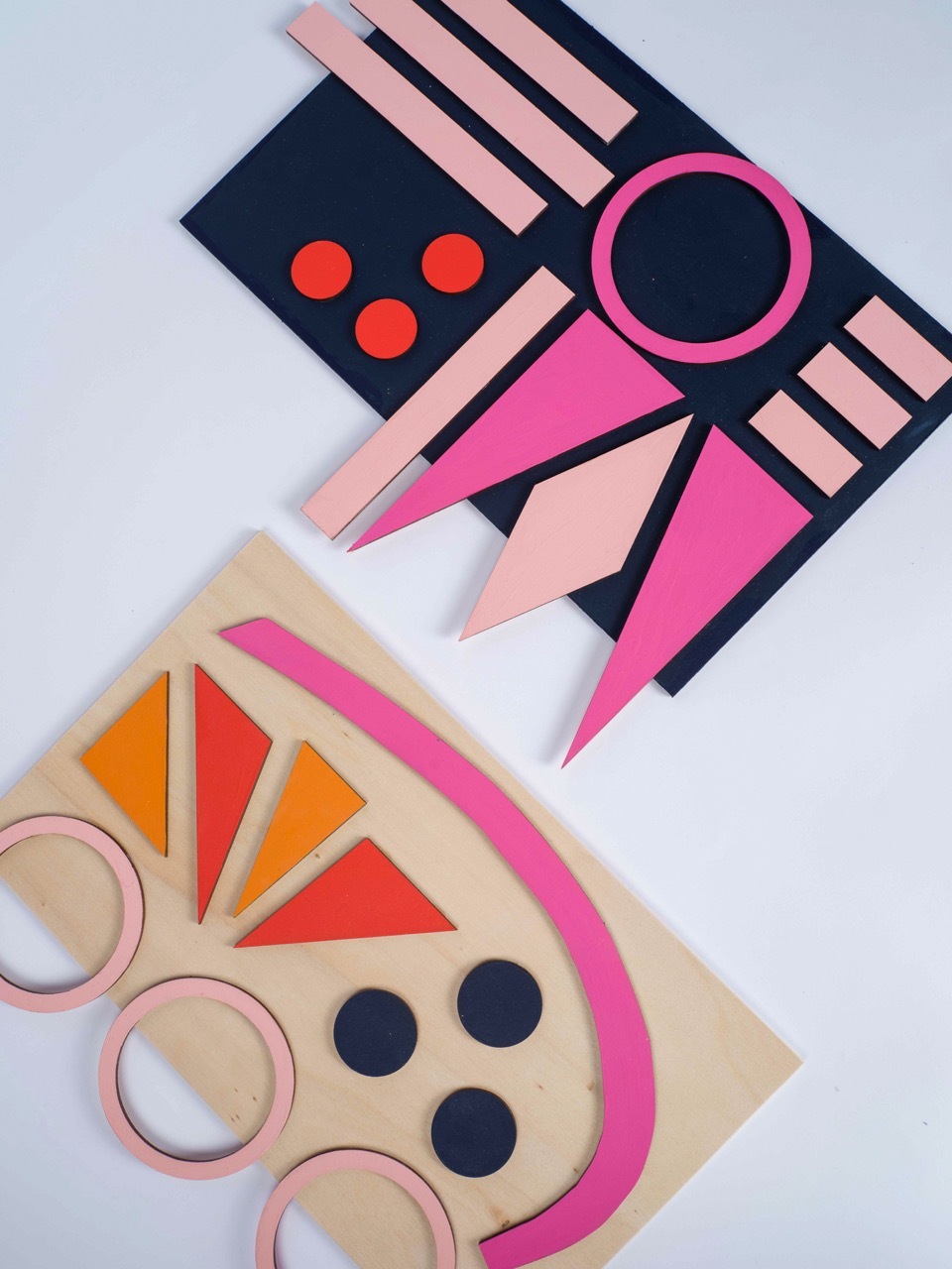 Two geometric paper cut-out compositions: top features navy rectangle with red circles, pink circle, and pink triangular shapes; bottom shows beige semicircle with orange triangular segments, dark circles, and pink circular rings.