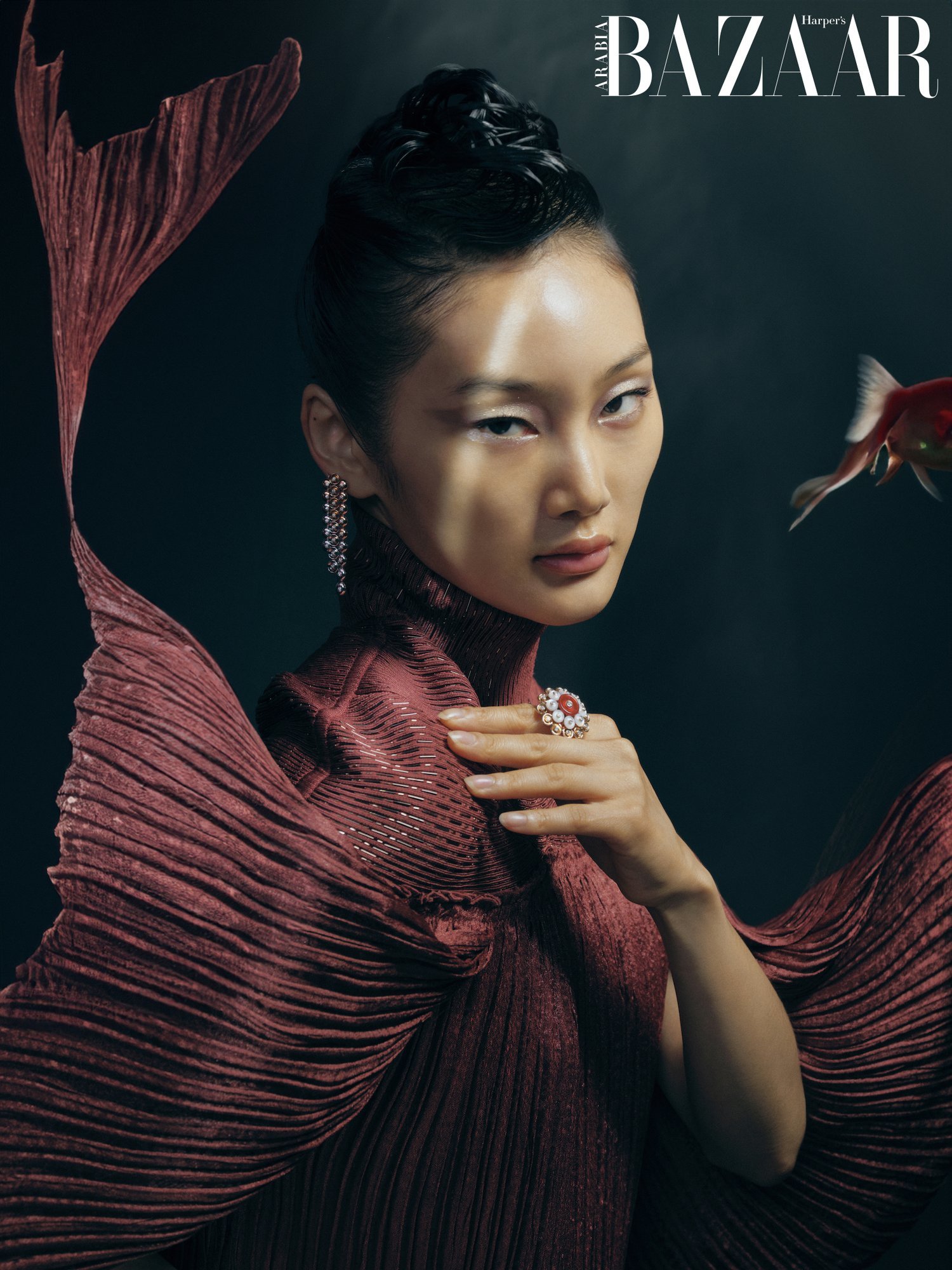 A model posing in a red fish-like dress as though underwater.