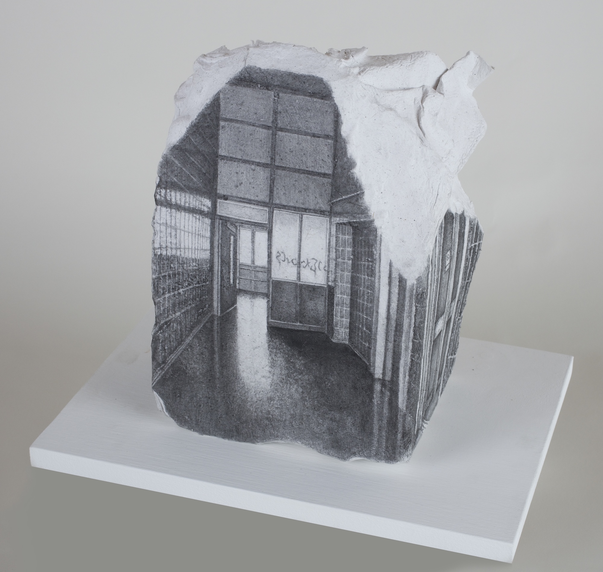 A monochrome drawing on a rough-edged stone block shows a room with tall windows, displayed on a white plinth.