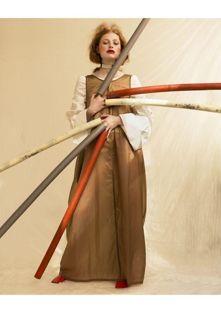 Image of a person wearing three bamboo tubes over their fingers on both hands. The person is placing both hands on their front.