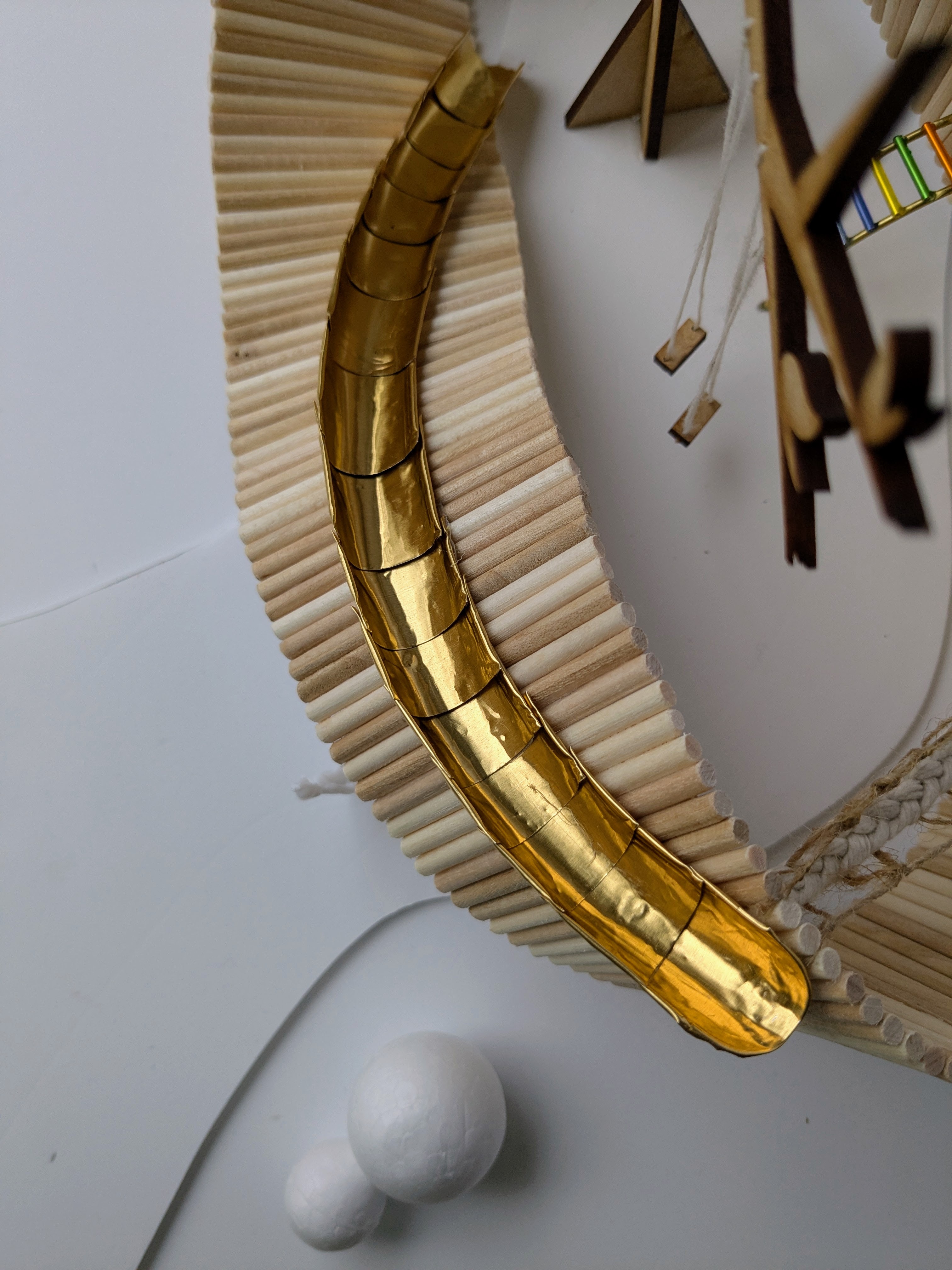Golden curved wing with ribbed bamboo flowing wood extending from segmented metallic shaft.
