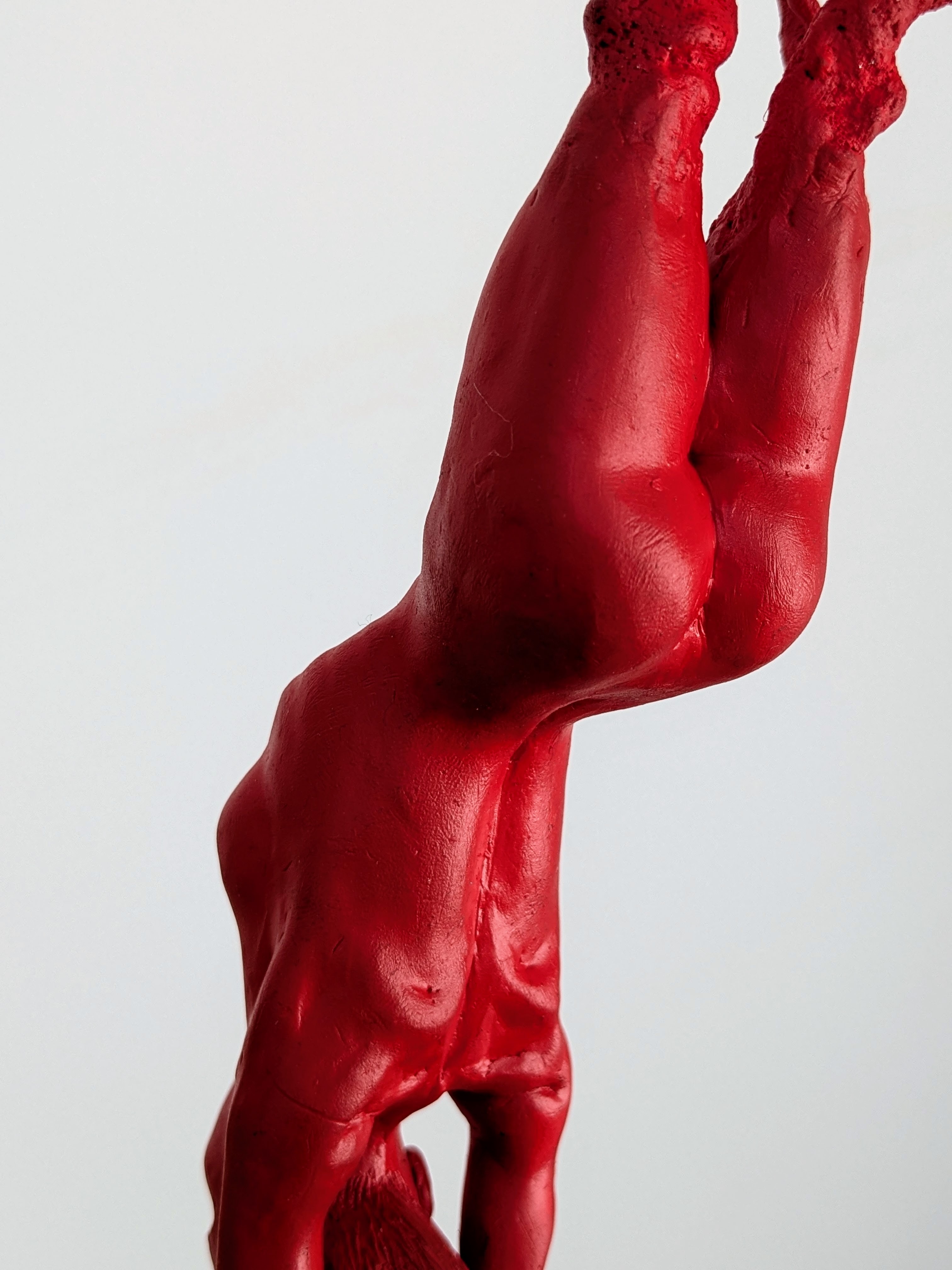 Small model of red body figure from behind and upside-down.