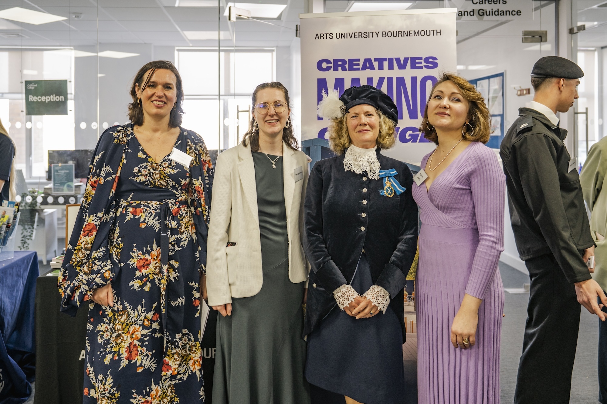 Dr H Walter, E Jones, H Conibear and K Lawton standing together in college space with purple 'CREATIVES MAKING' banner visible on wall behind them
