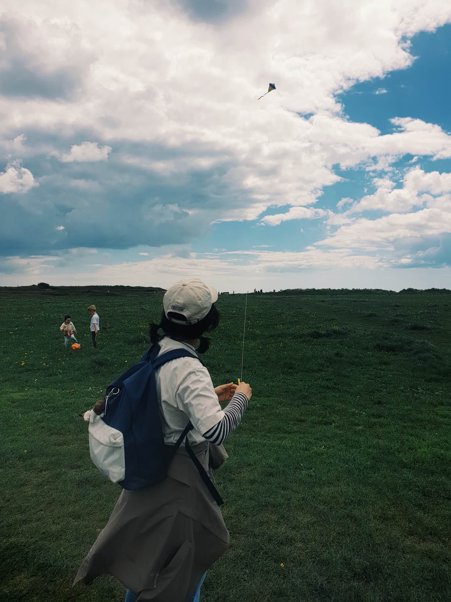 A person at Hengistbury Head with deep green grass and a cloudy sky.