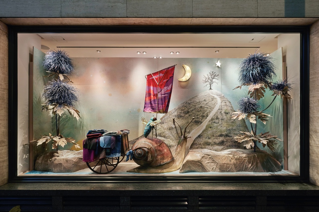 A decorative shop window with a snail carriage and nature.